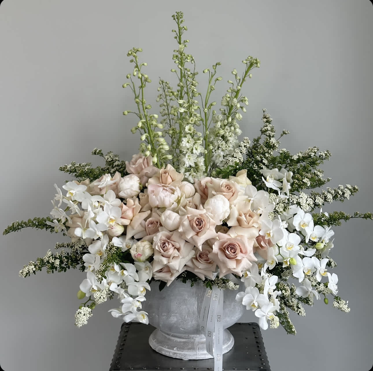 Large pale pink and white floral arrangement in a gray vase