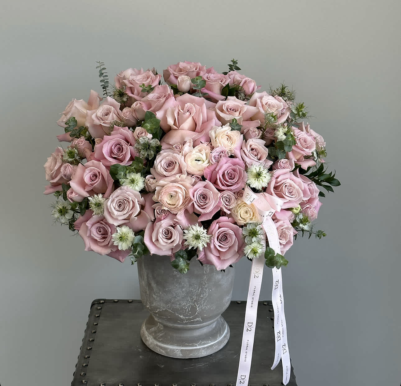 Pink rose bouquet in a gray urn vase with ribbon tails