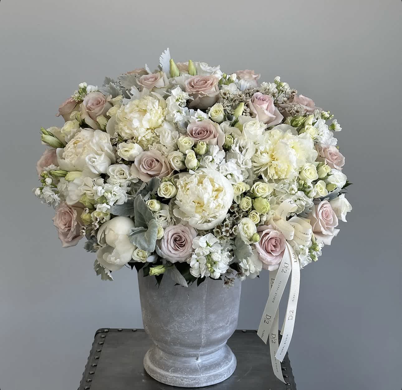 Blush and white rose bouquet in a gray pedestal vase