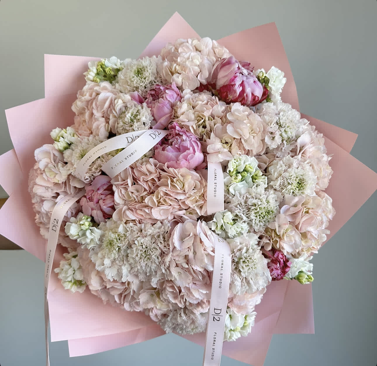 Large pastel bouquet of pink and white flowers wrapped in pink paper