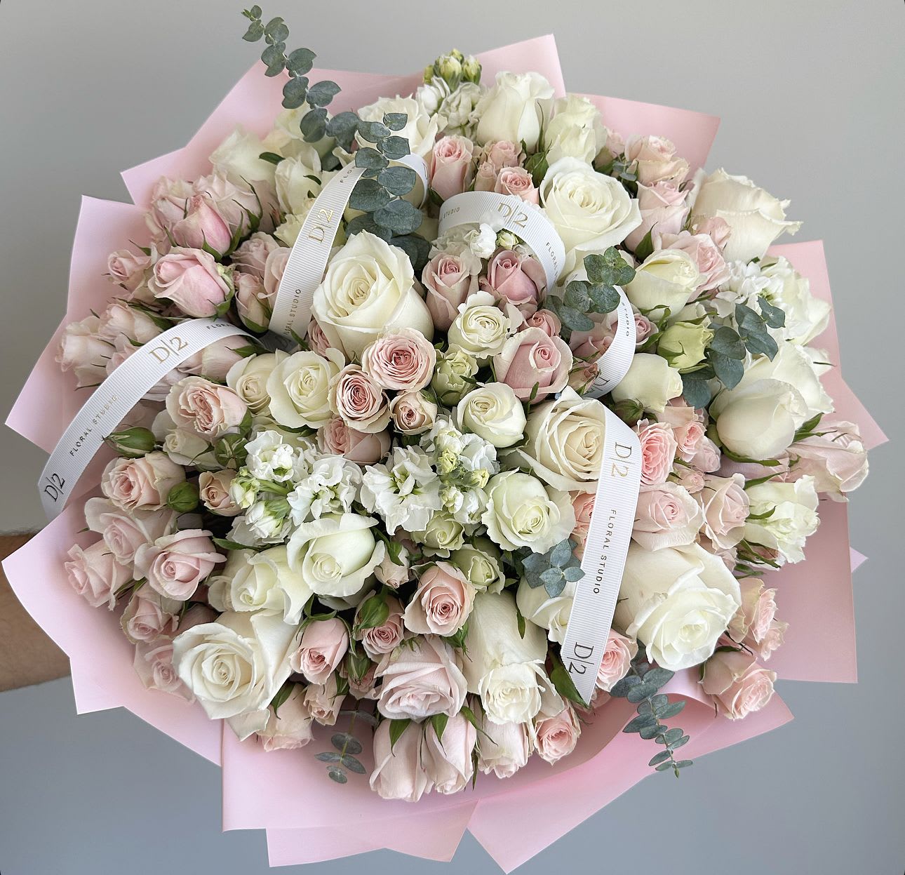 Large bouquet of white and blush roses wrapped in pink paper