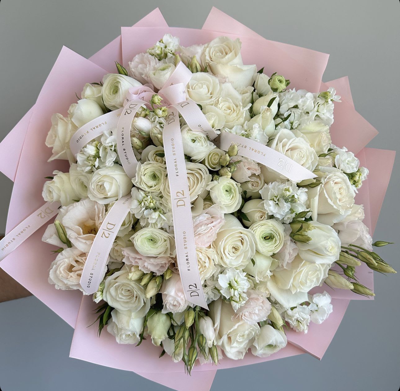 Bouquet of white roses and pale pink flowers wrapped in pink paper
