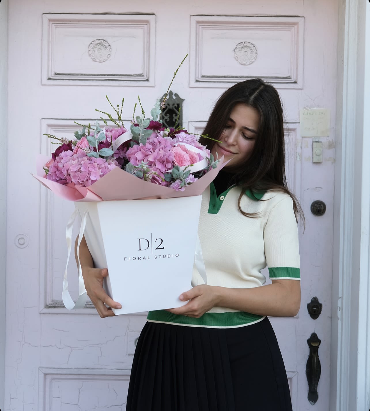 Woman holding a large pink flower bouquet in a white box