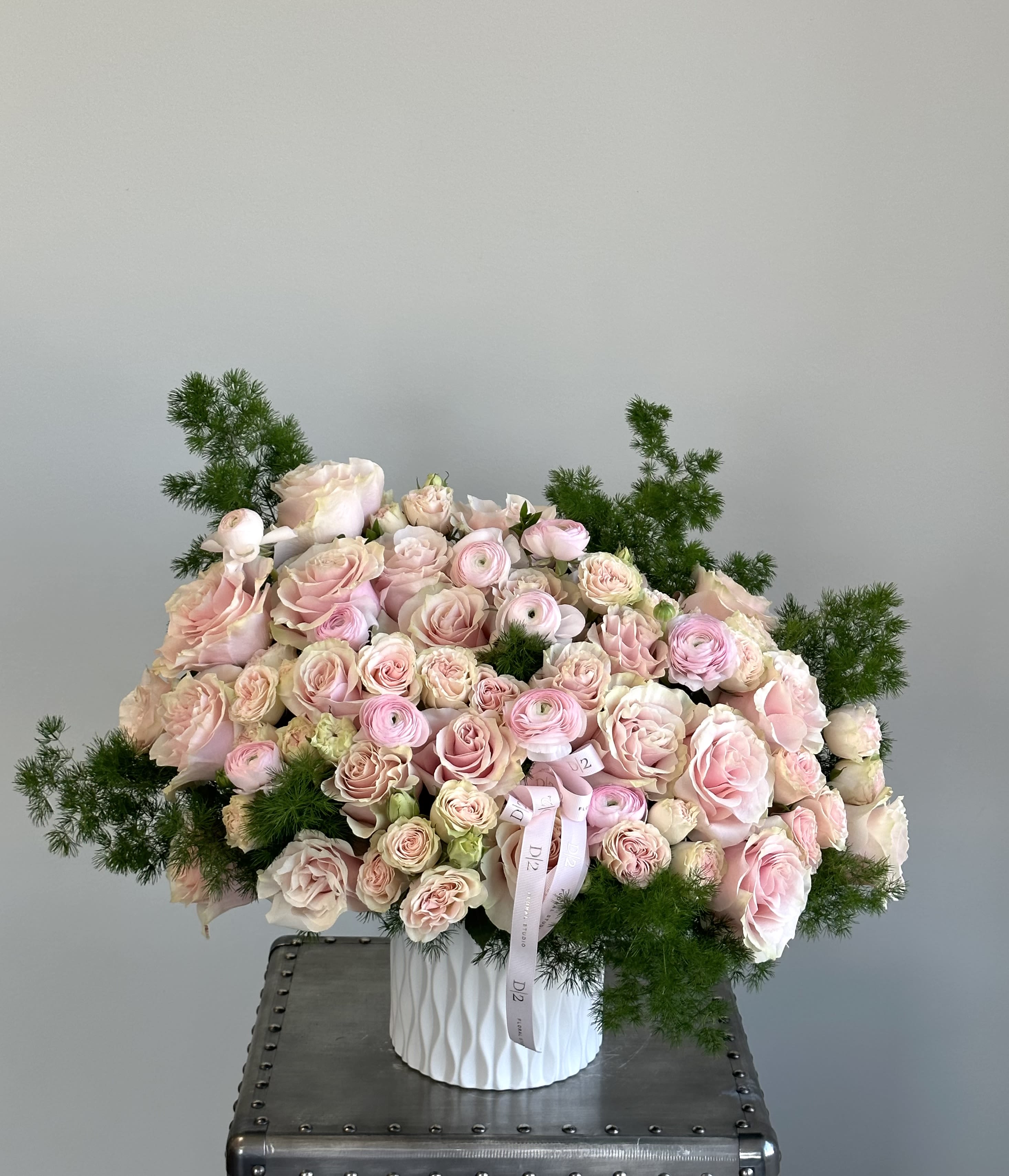 Large bouquet of pale pink roses and ranunculus in a white vase