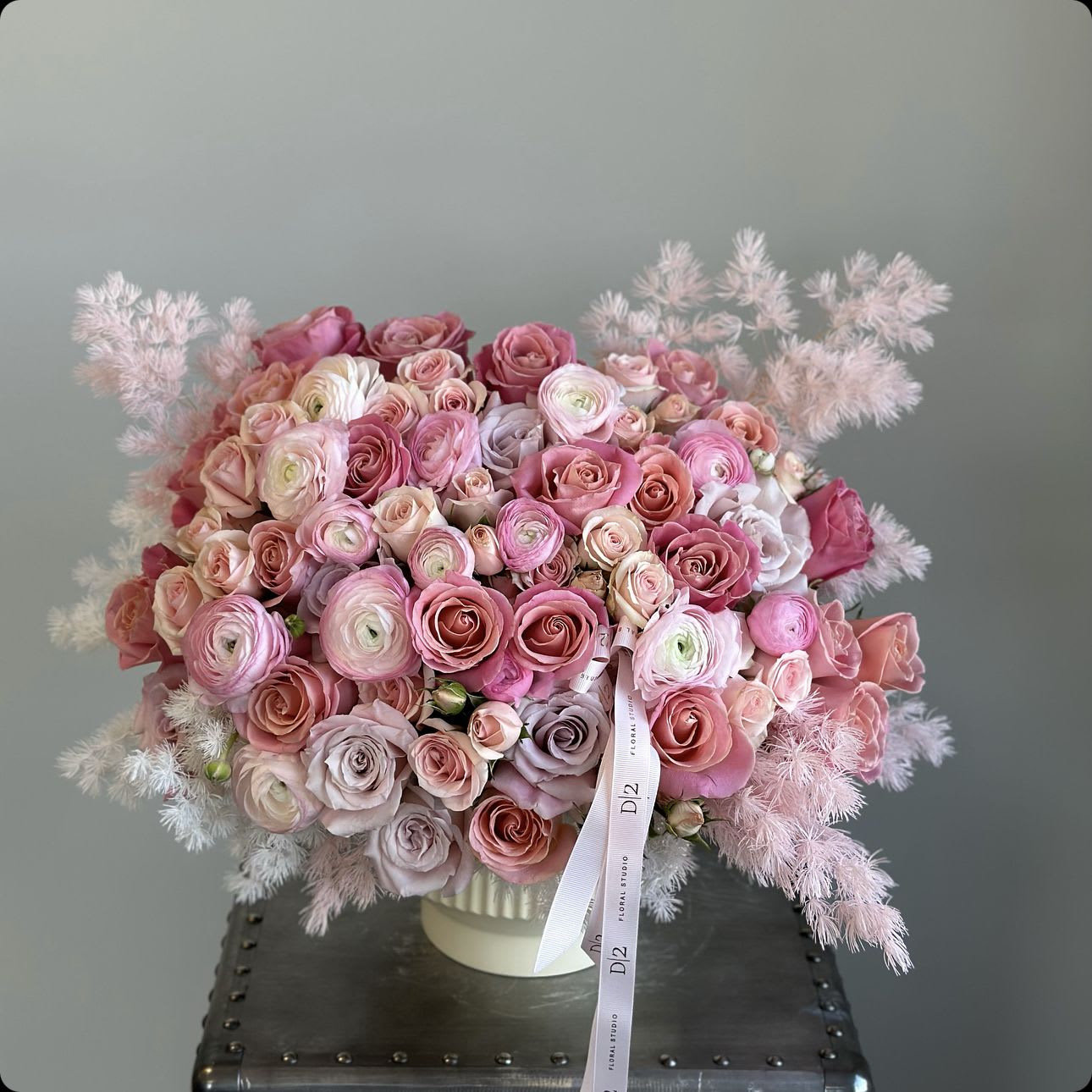 Pink and blush rose bouquet in a white vase with feathery accents