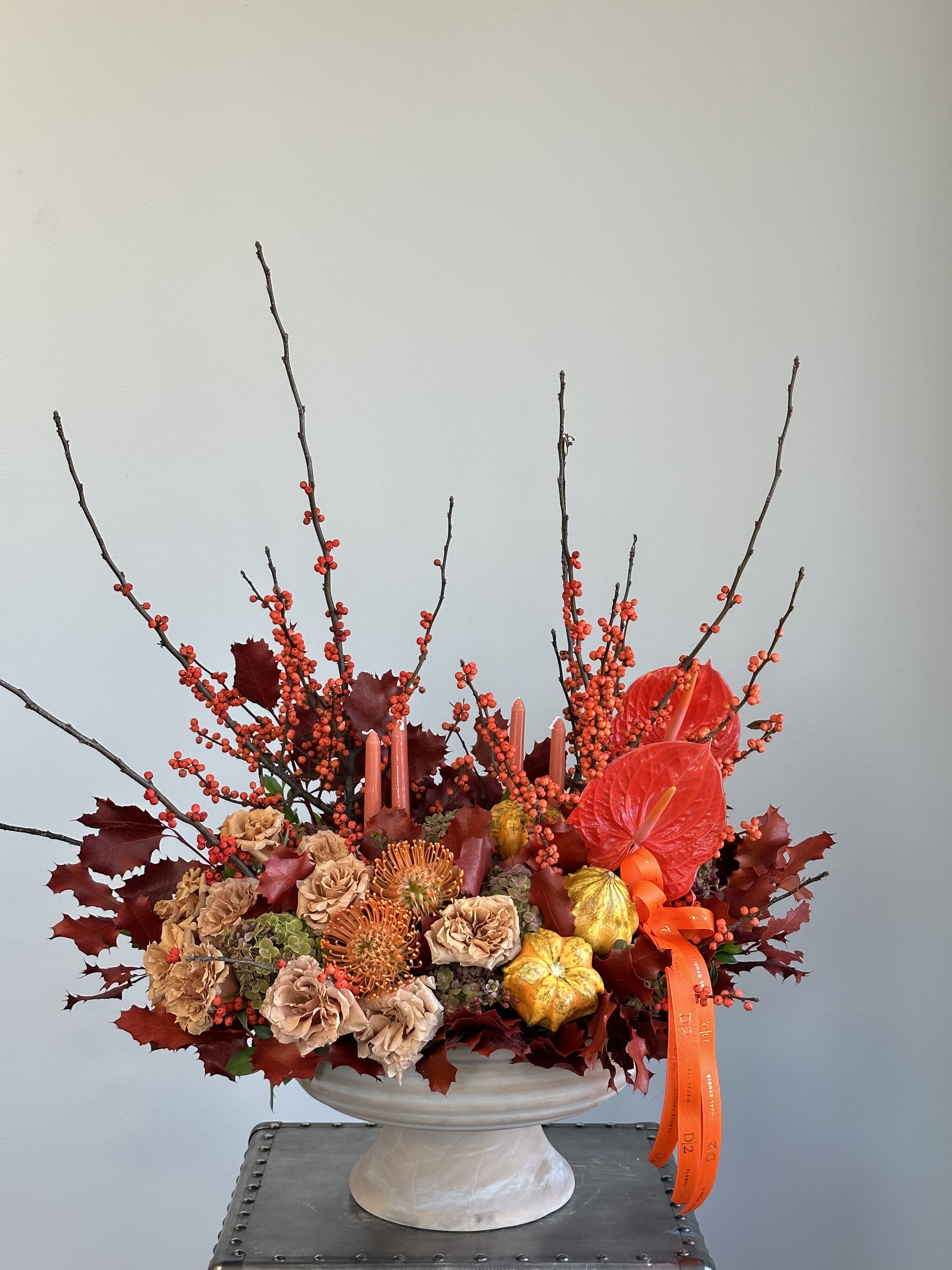 Autumn floral arrangement in a white pedestal vase with orange ribbon