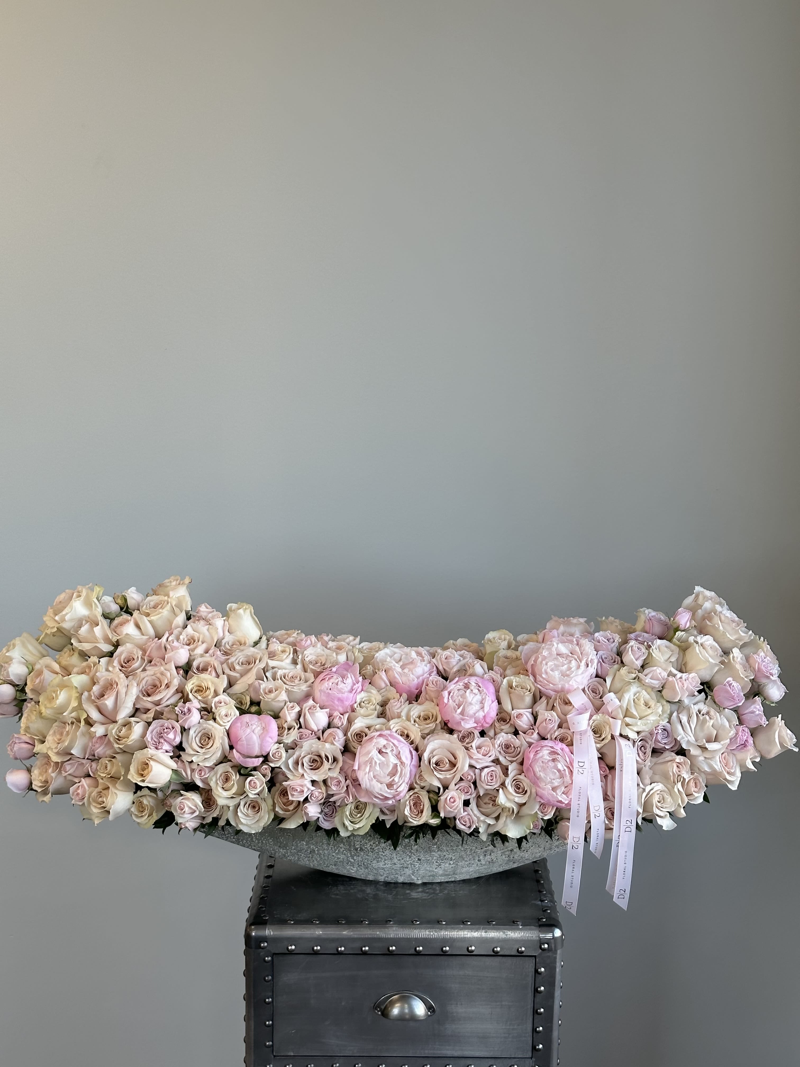 Low arrangement of pale pink and cream roses in a gray bowl
