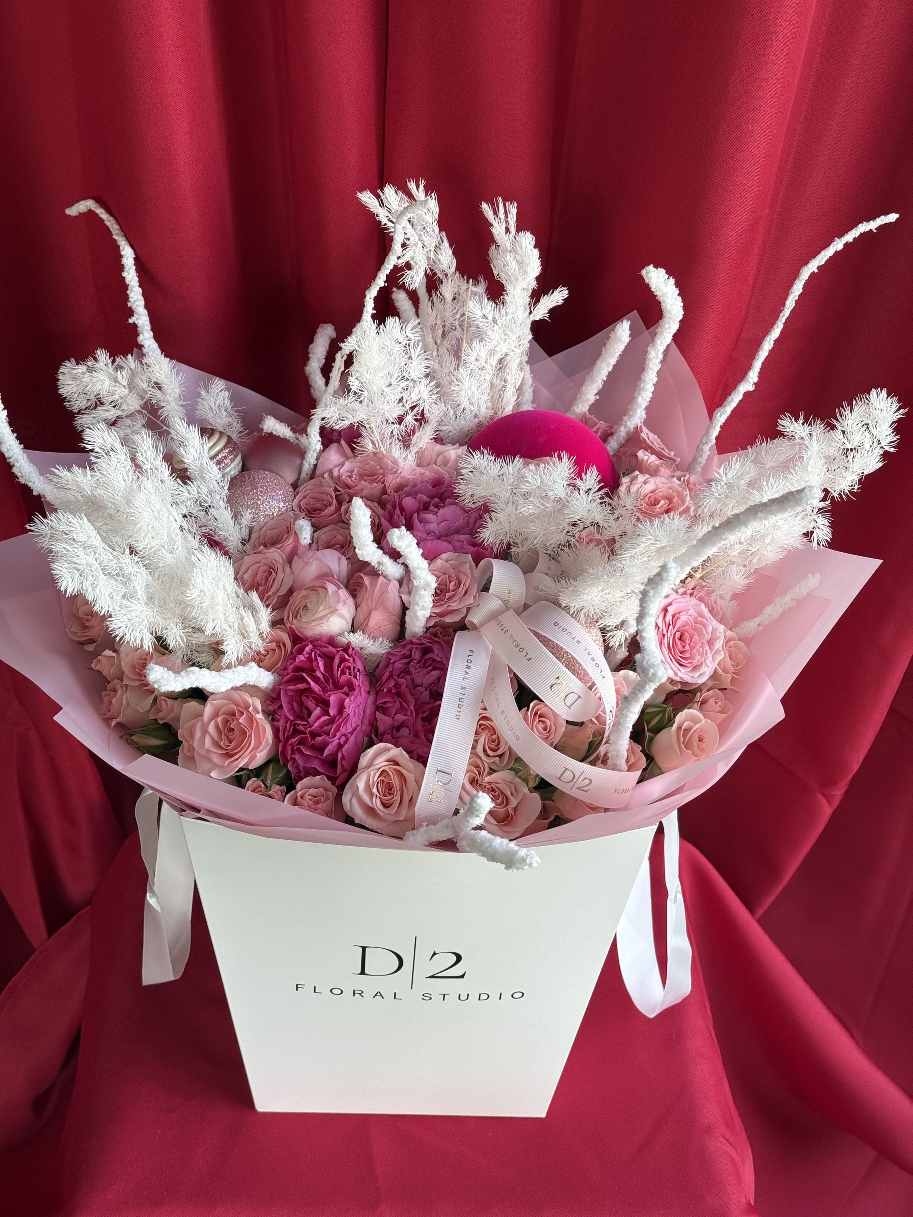Pink roses and peonies in a white gift box with white decorative branches
