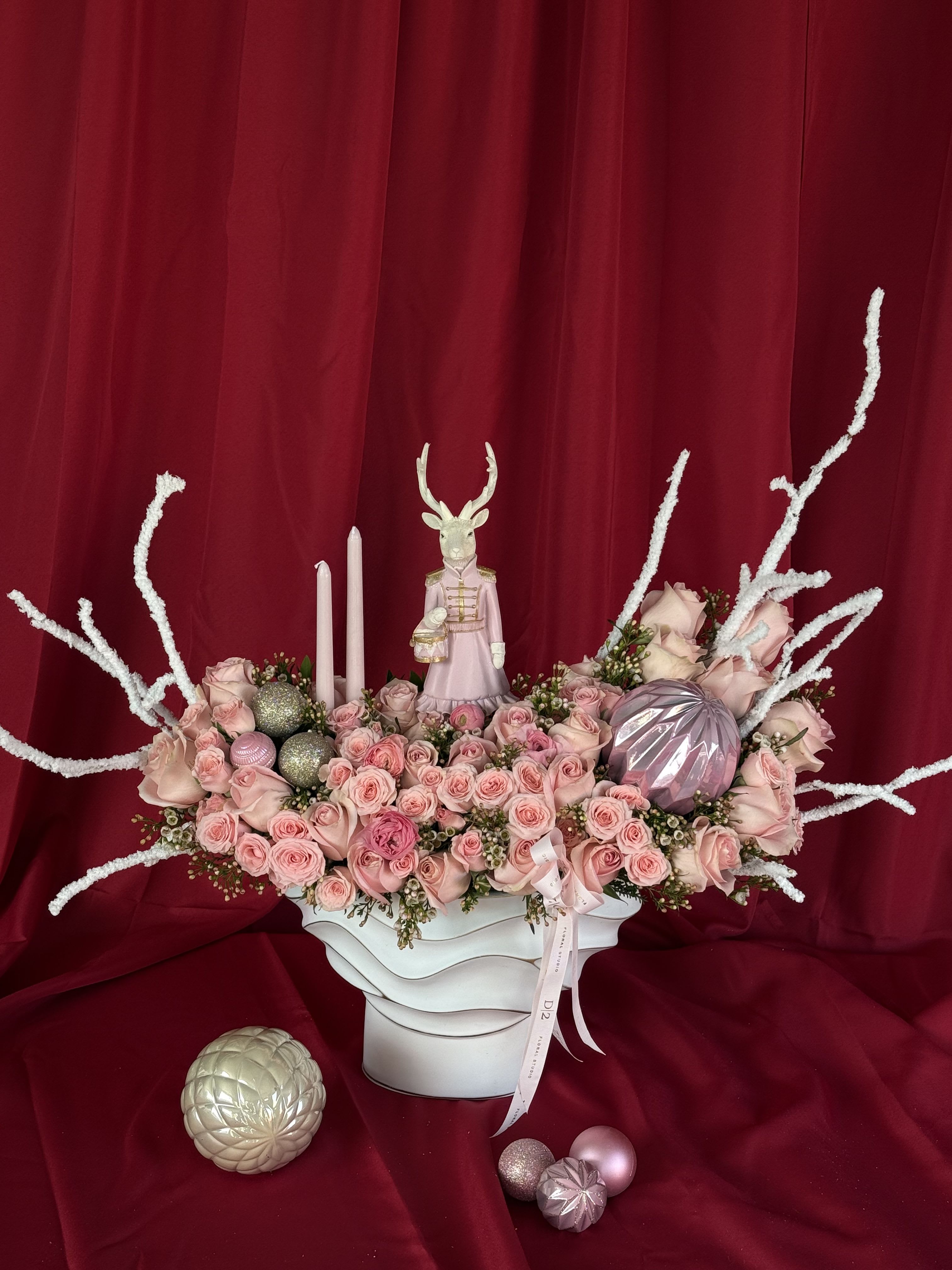 Pink rose arrangement in a white vase with candles and decorative ornaments