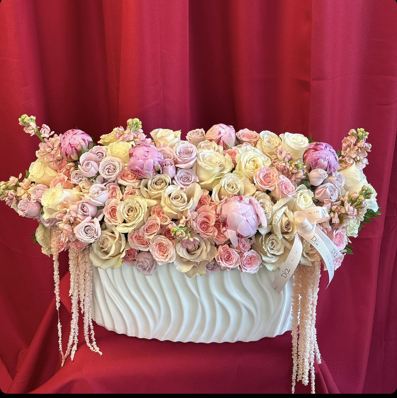 Pastel roses and peonies arranged in a white vase