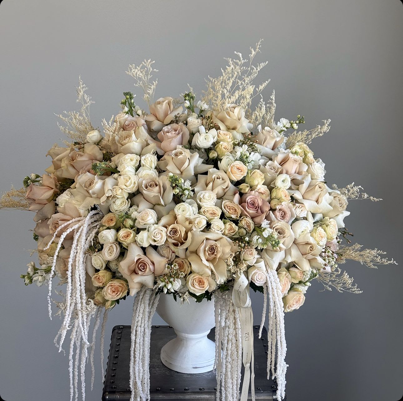 Large cream and blush rose arrangement in a white urn vase