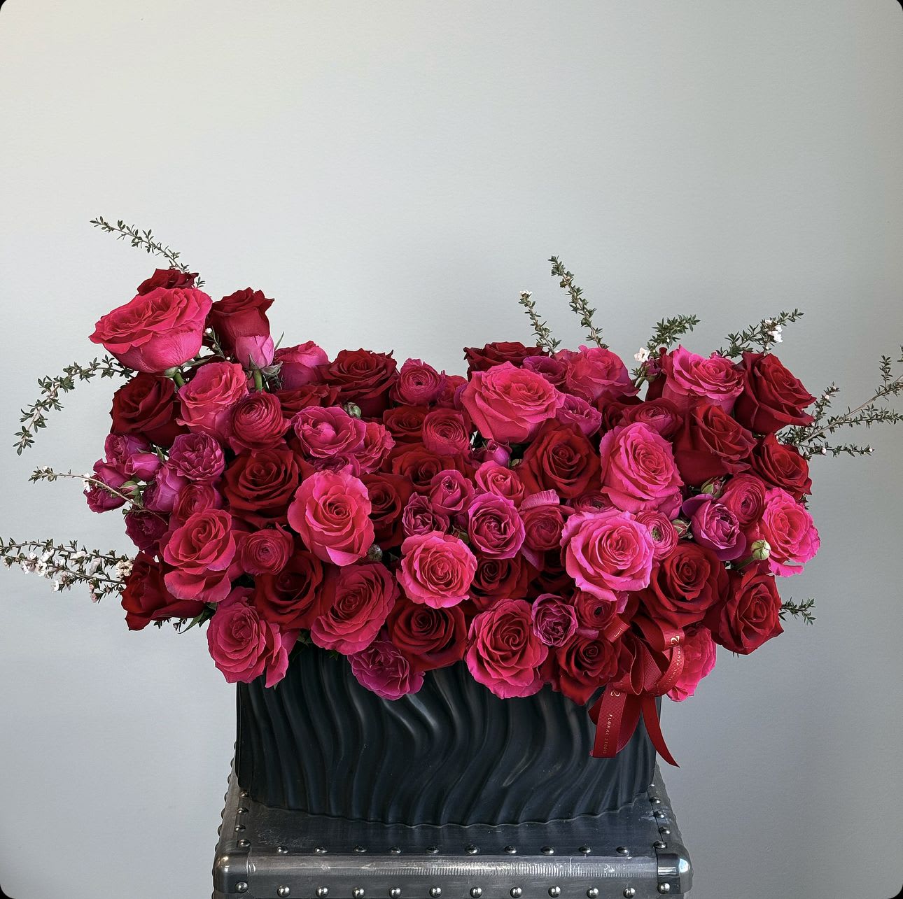 Large bouquet of pink and red roses in a dark vase