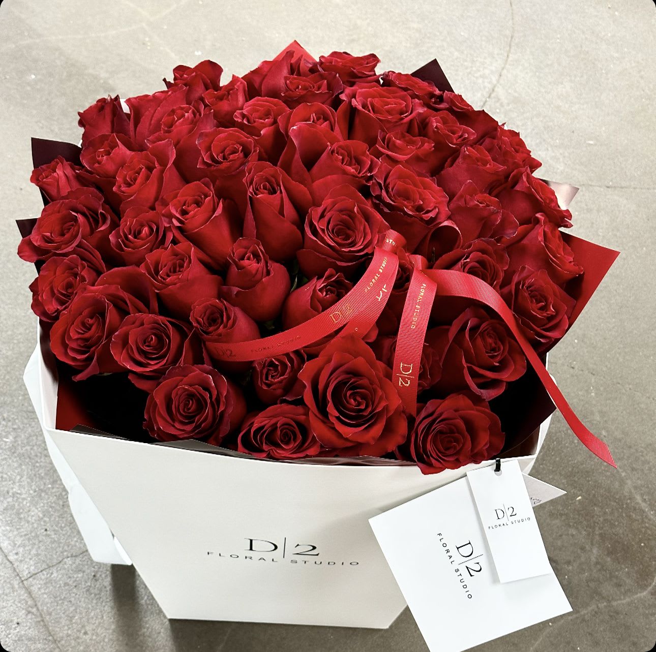 Large bouquet of red roses in a white box with a red ribbon