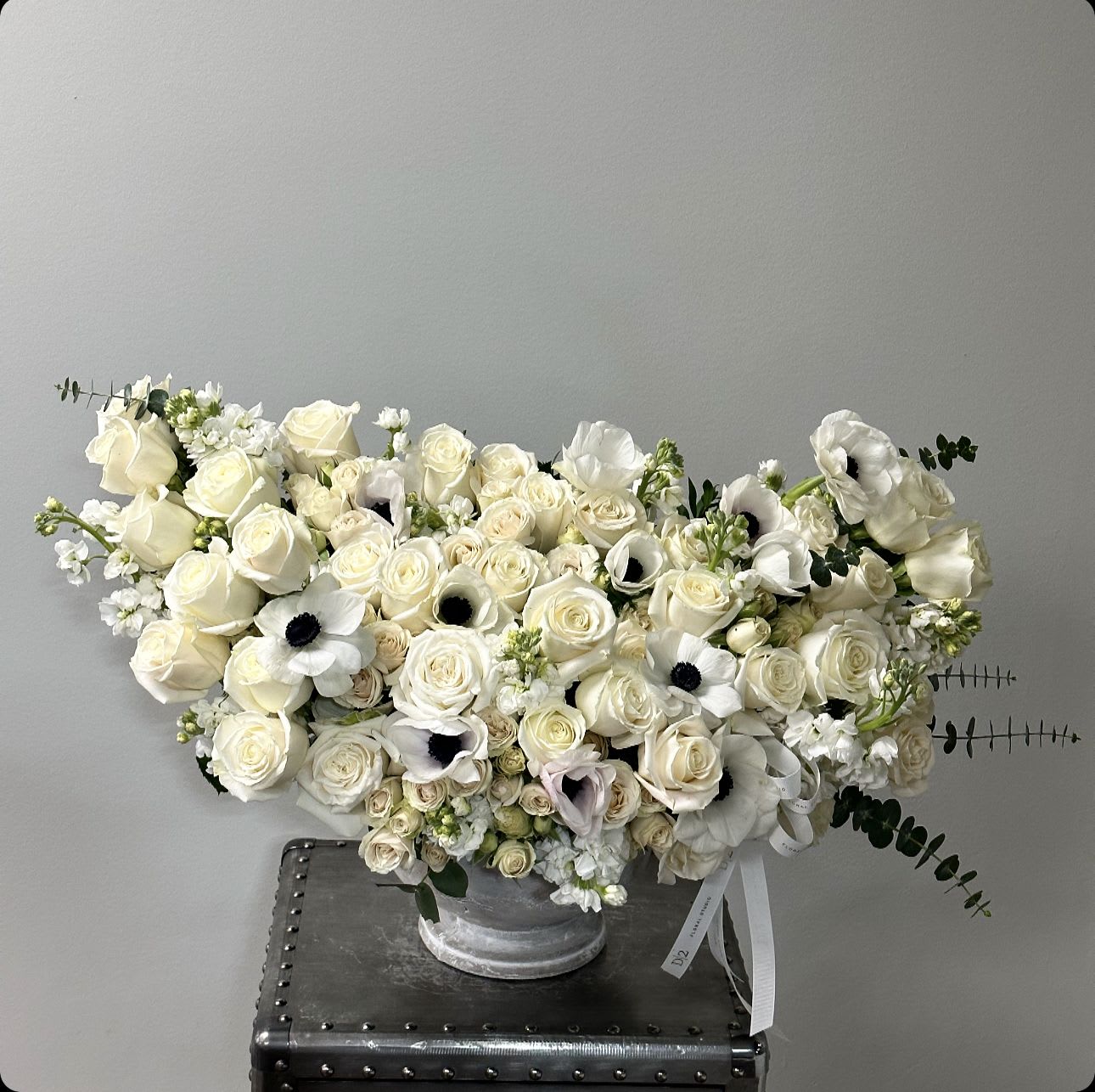 Cream rose arrangement with white anemones in a silver vase