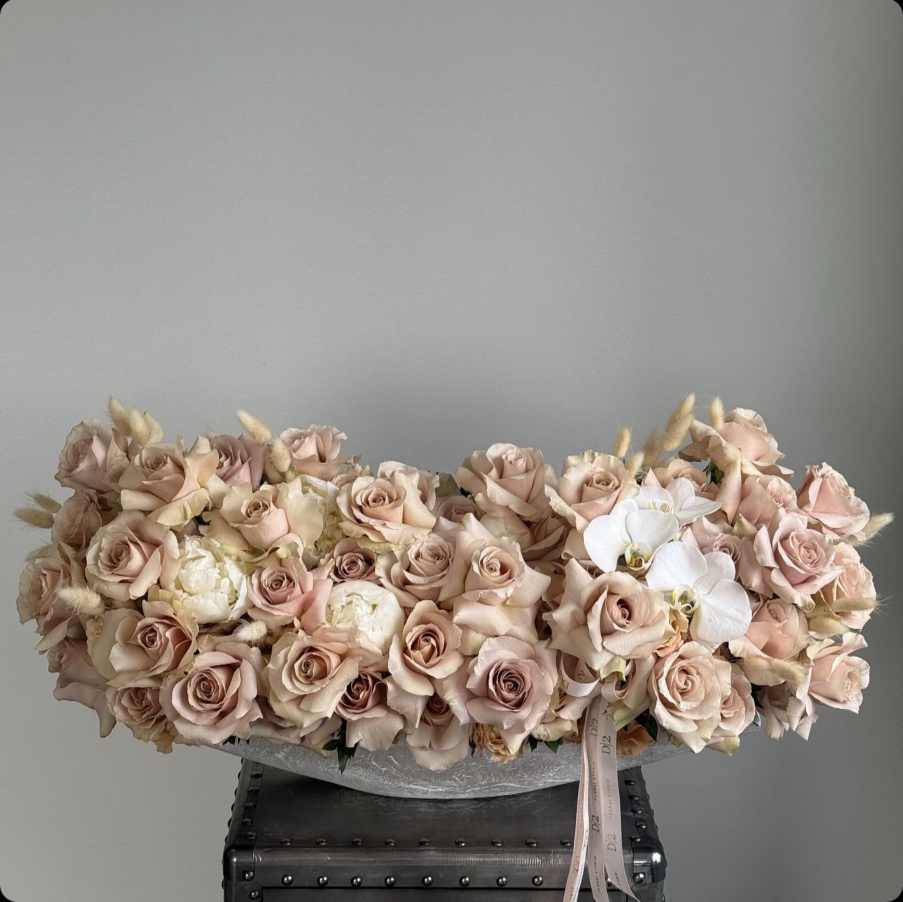 Low arrangement of blush roses and white orchids in a shallow container