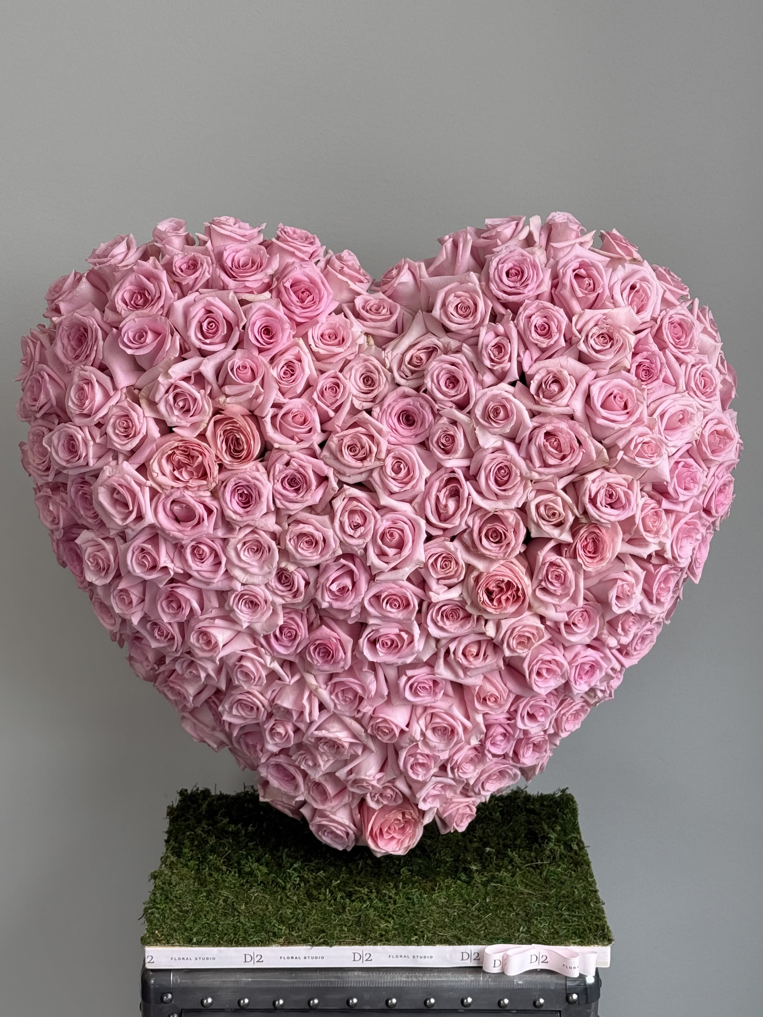 Heart-shaped arrangement of pink roses on a moss-covered base
