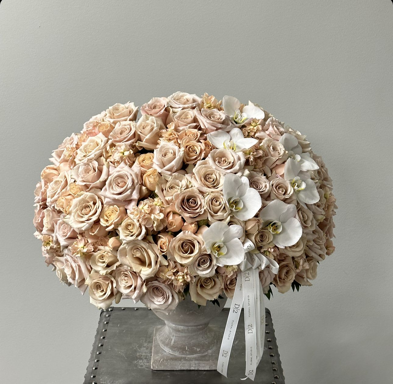 Large bouquet of blush roses and white orchids in a stone vase