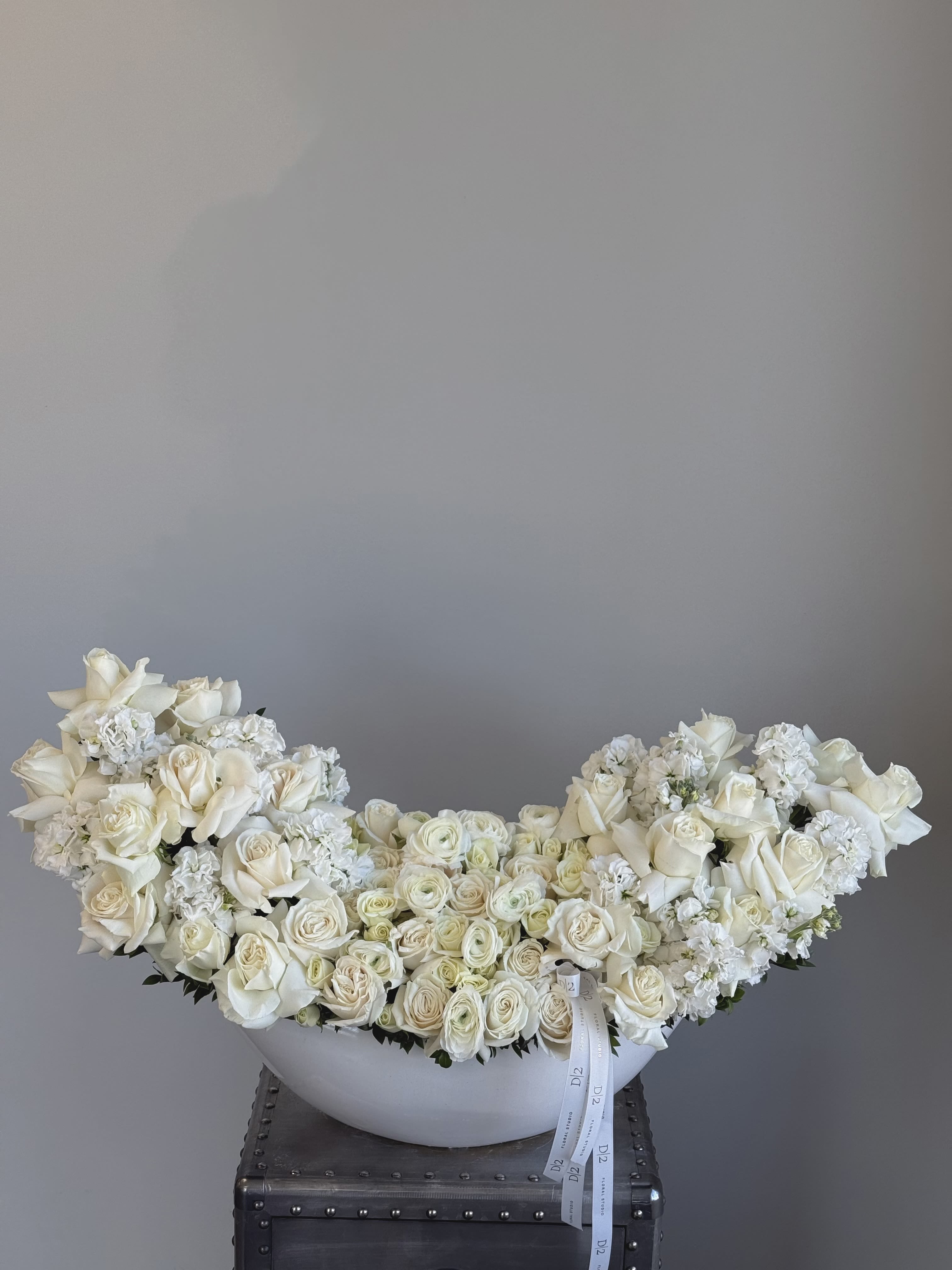 Large white rose arrangement in a white bowl vase