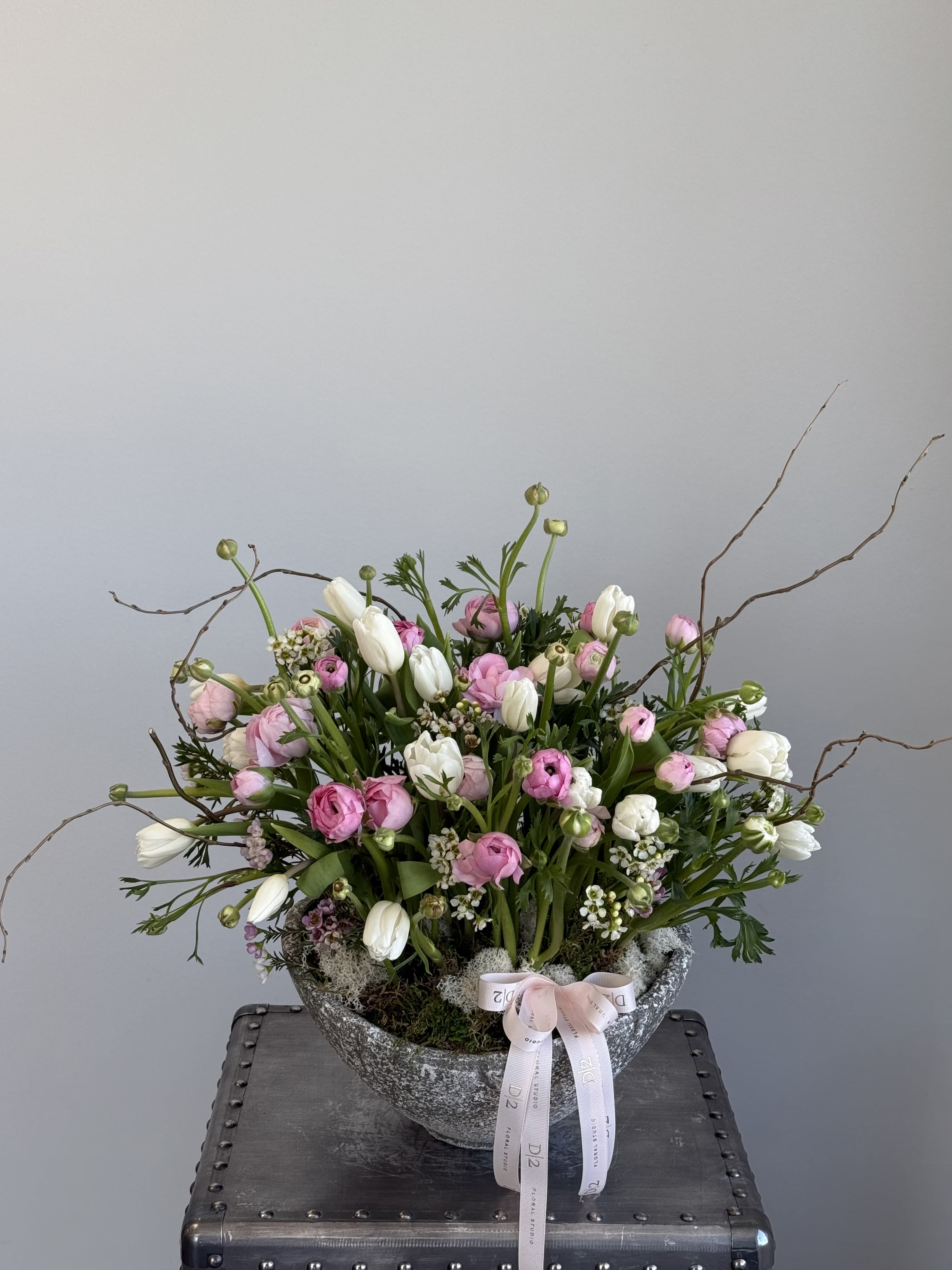 Pink and white floral arrangement in a stone bowl with ribbon