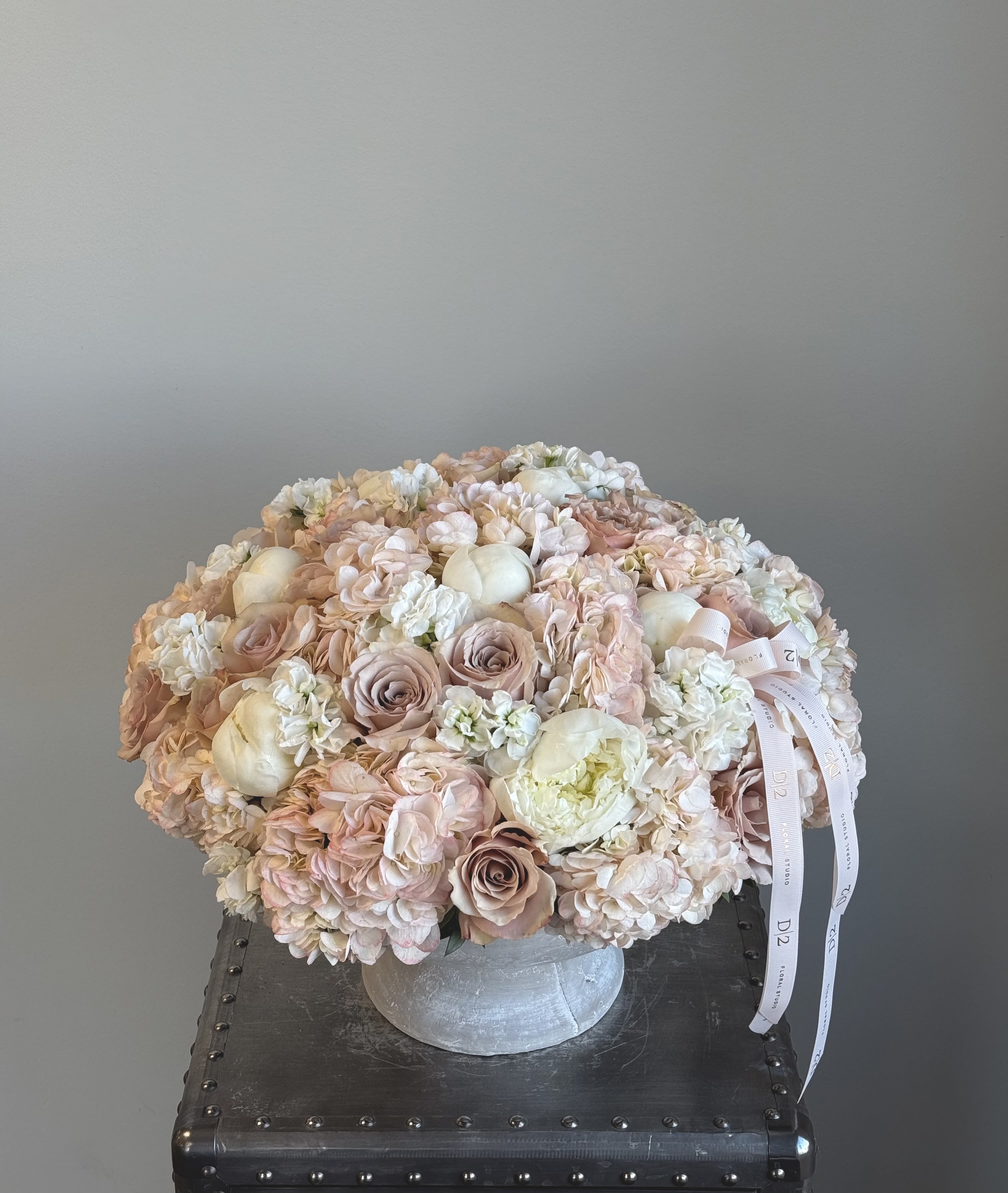 Round bouquet of blush and white flowers in a silver vase