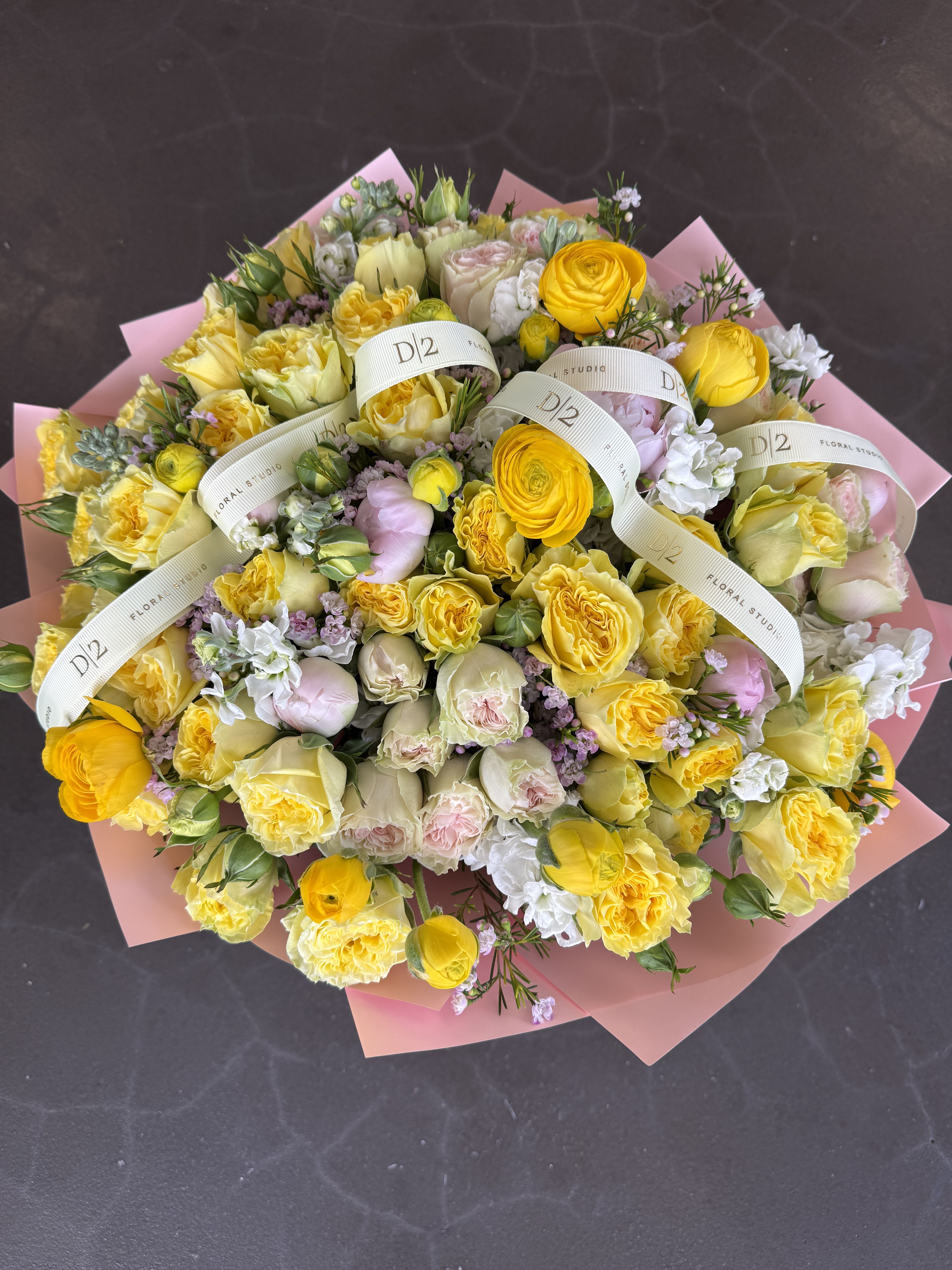 Large bouquet of yellow and pale pink roses wrapped in pink paper