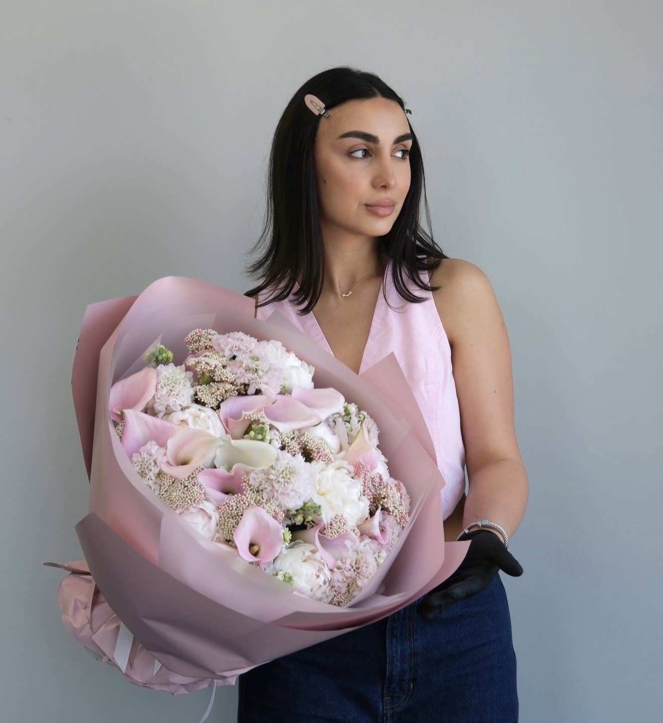 Woman holding a large bouquet of pale pink and white flowers wrapped in pink paper