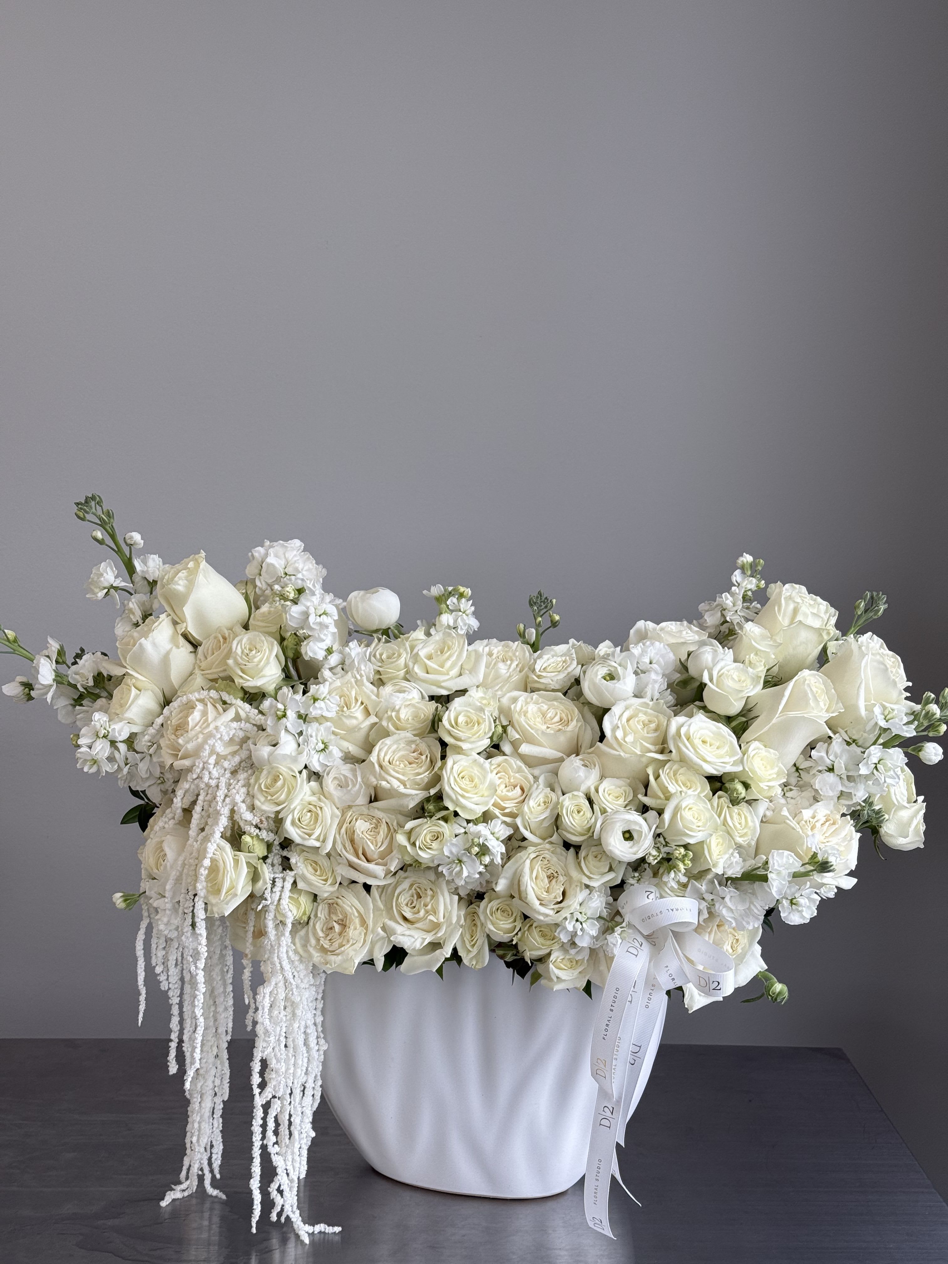 White roses and calla lilies arranged in a white vase