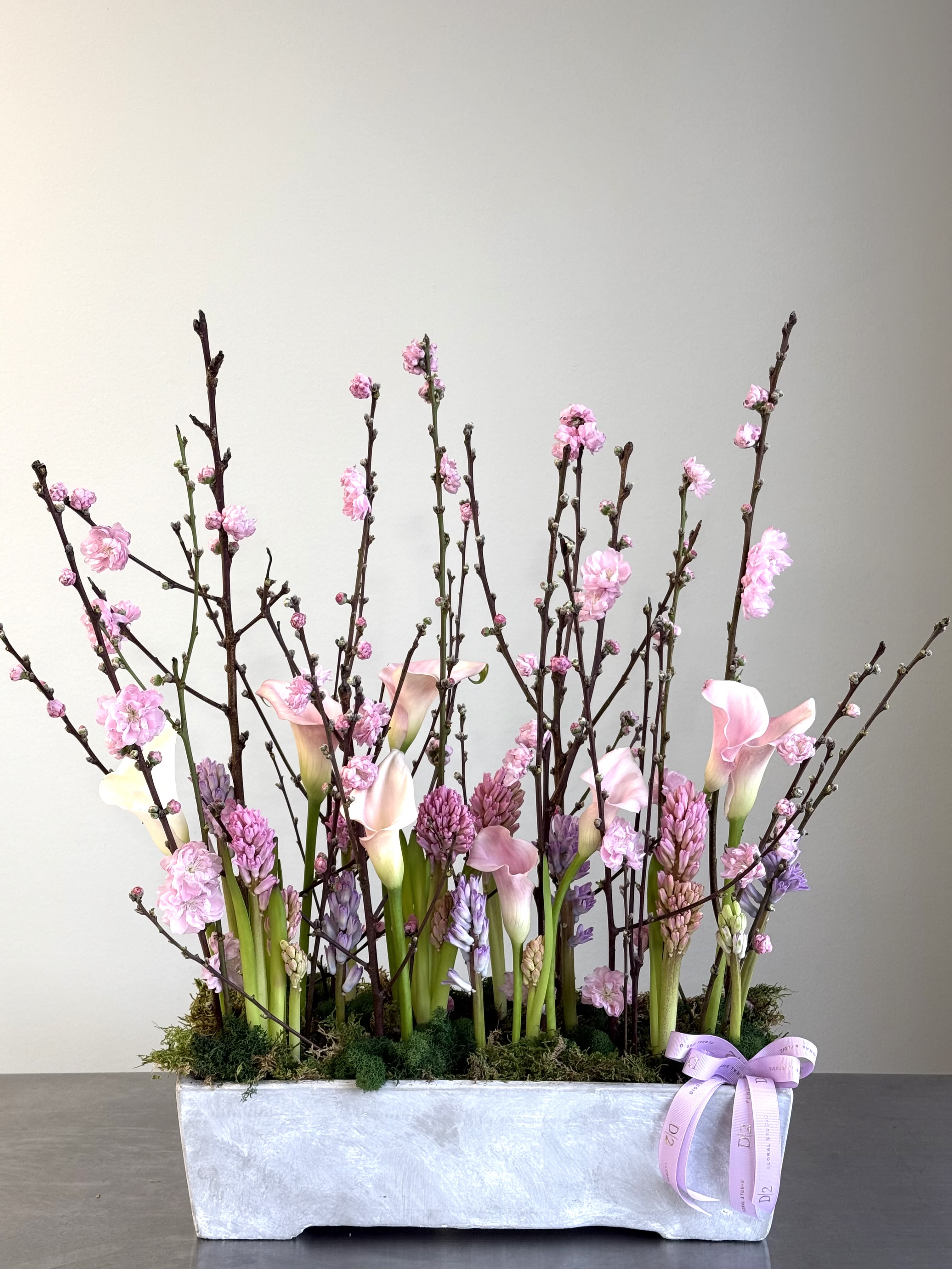 Pink calla lilies and blossoms in a rectangular silver planter