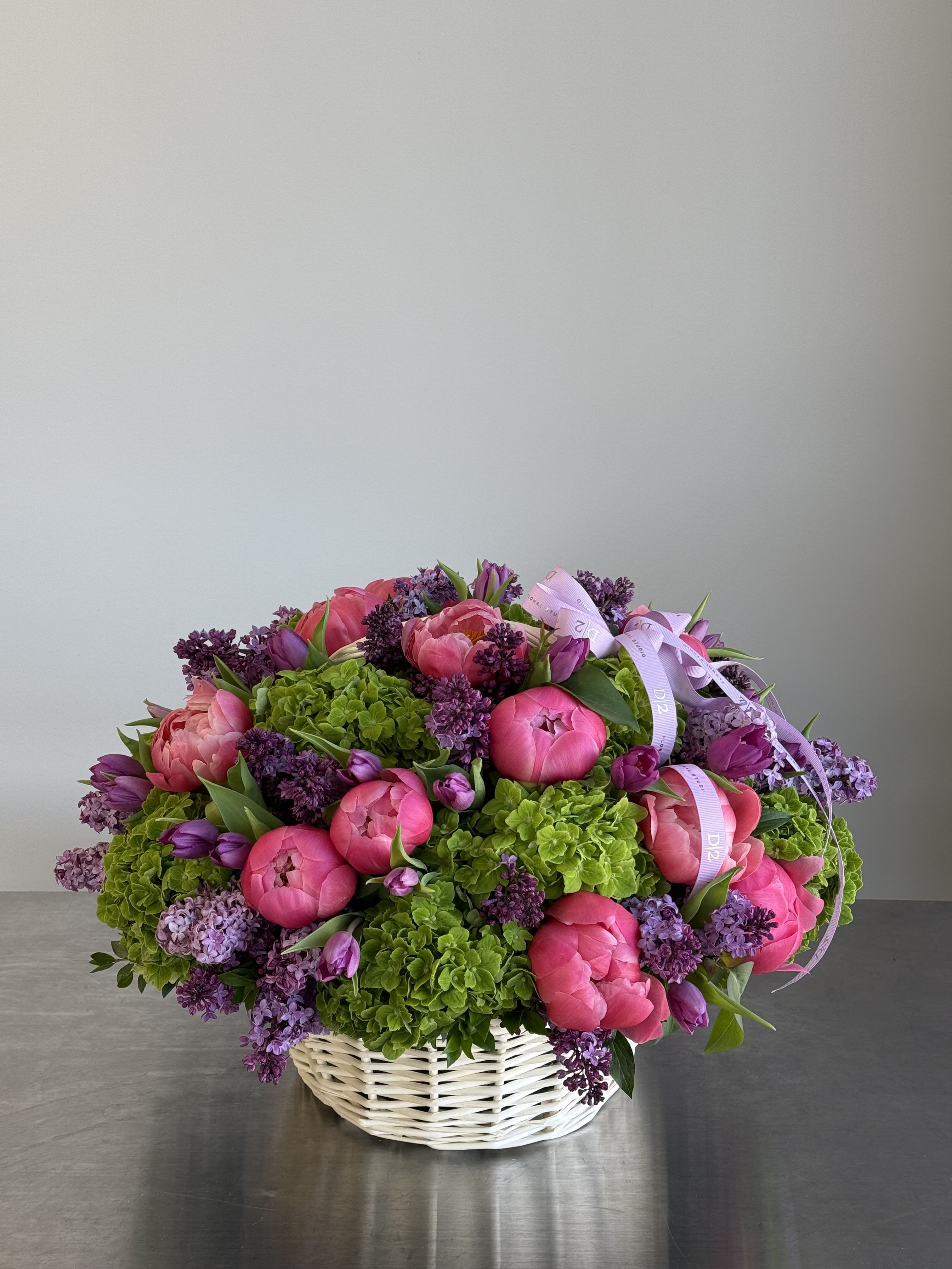 Pink peonies and purple lilacs in a white basket