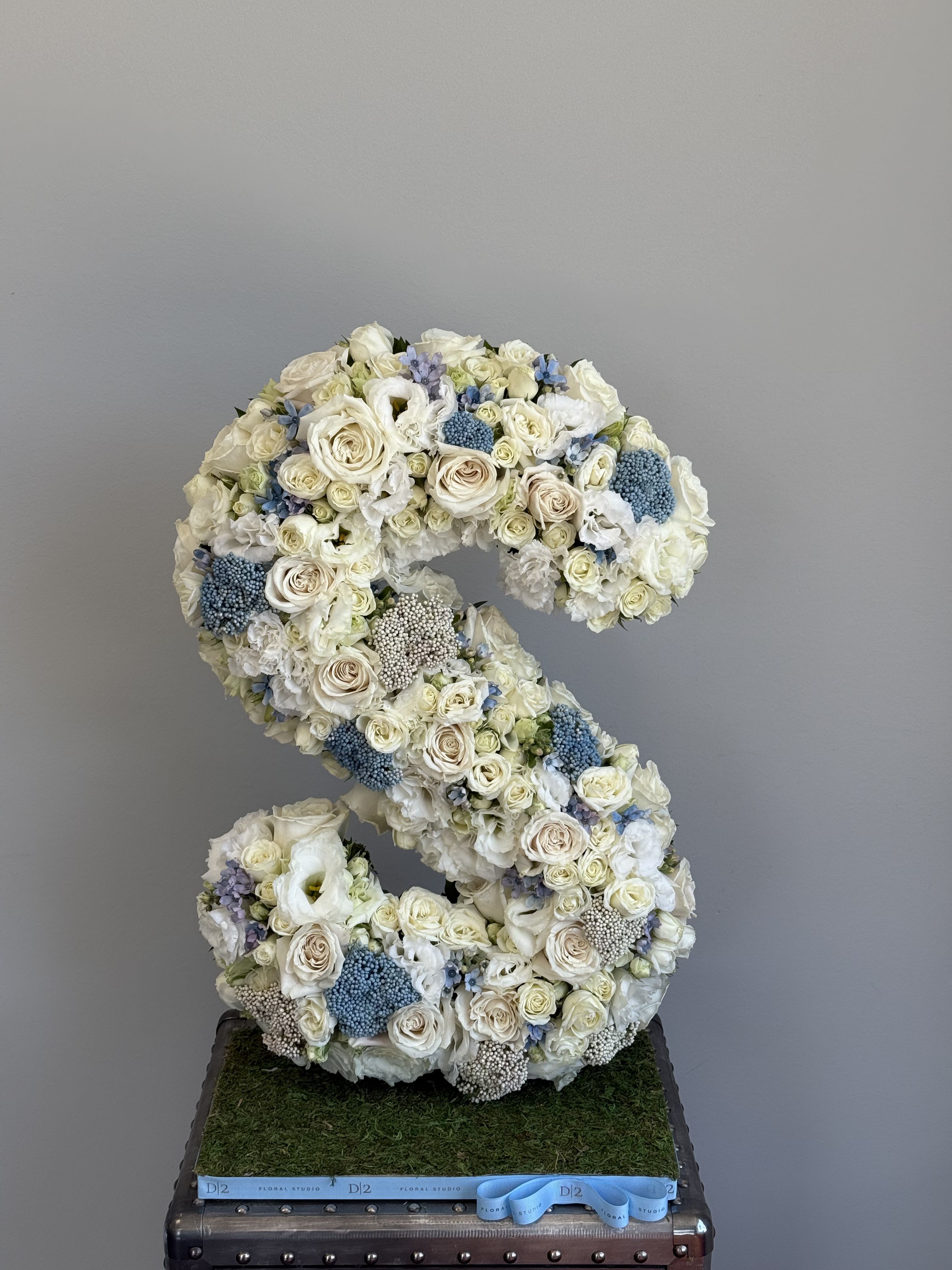 Large floral letter S made of white and pale blue flowers