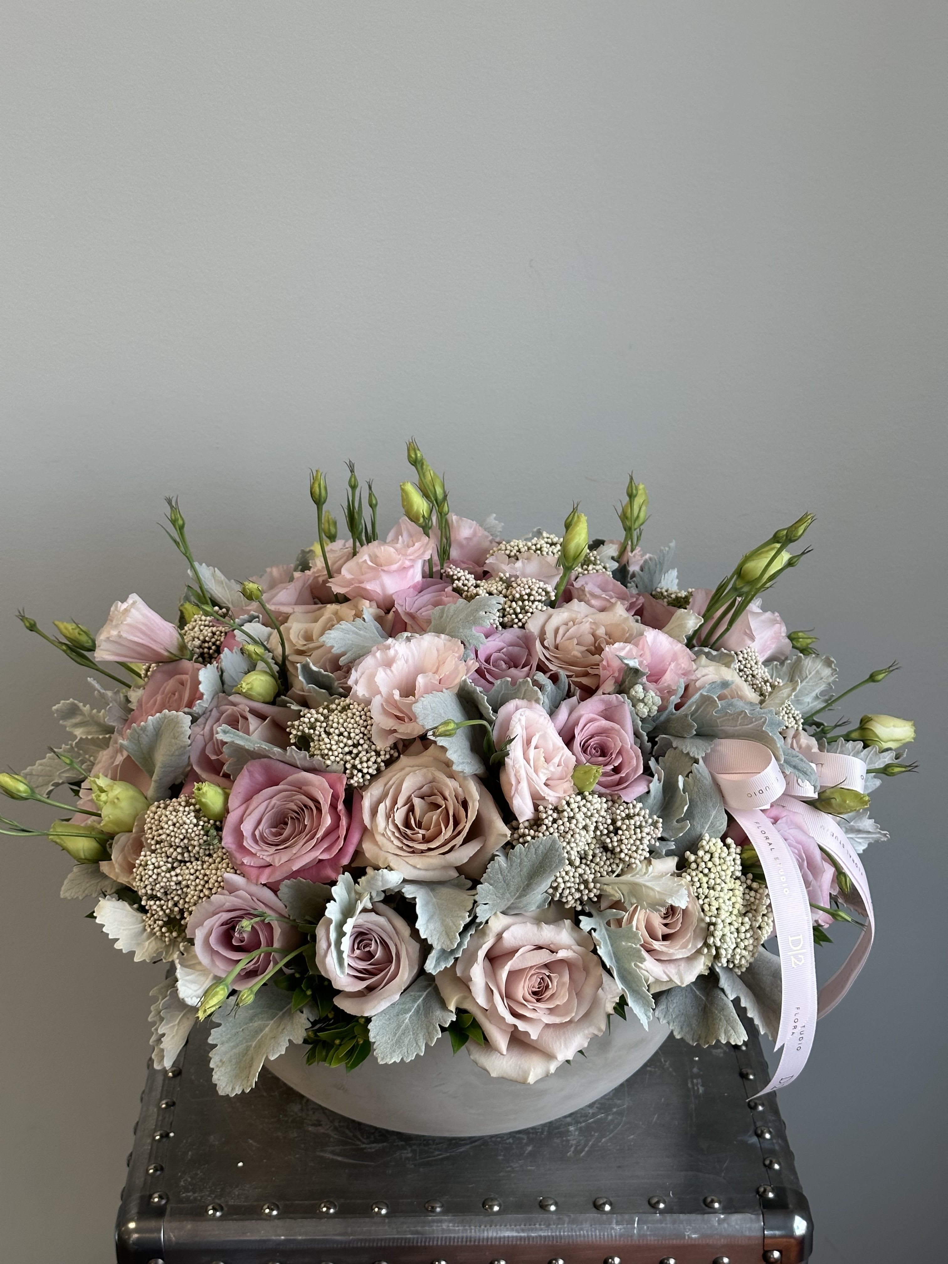 Round bouquet of blush roses and pale pink blooms in a gray box
