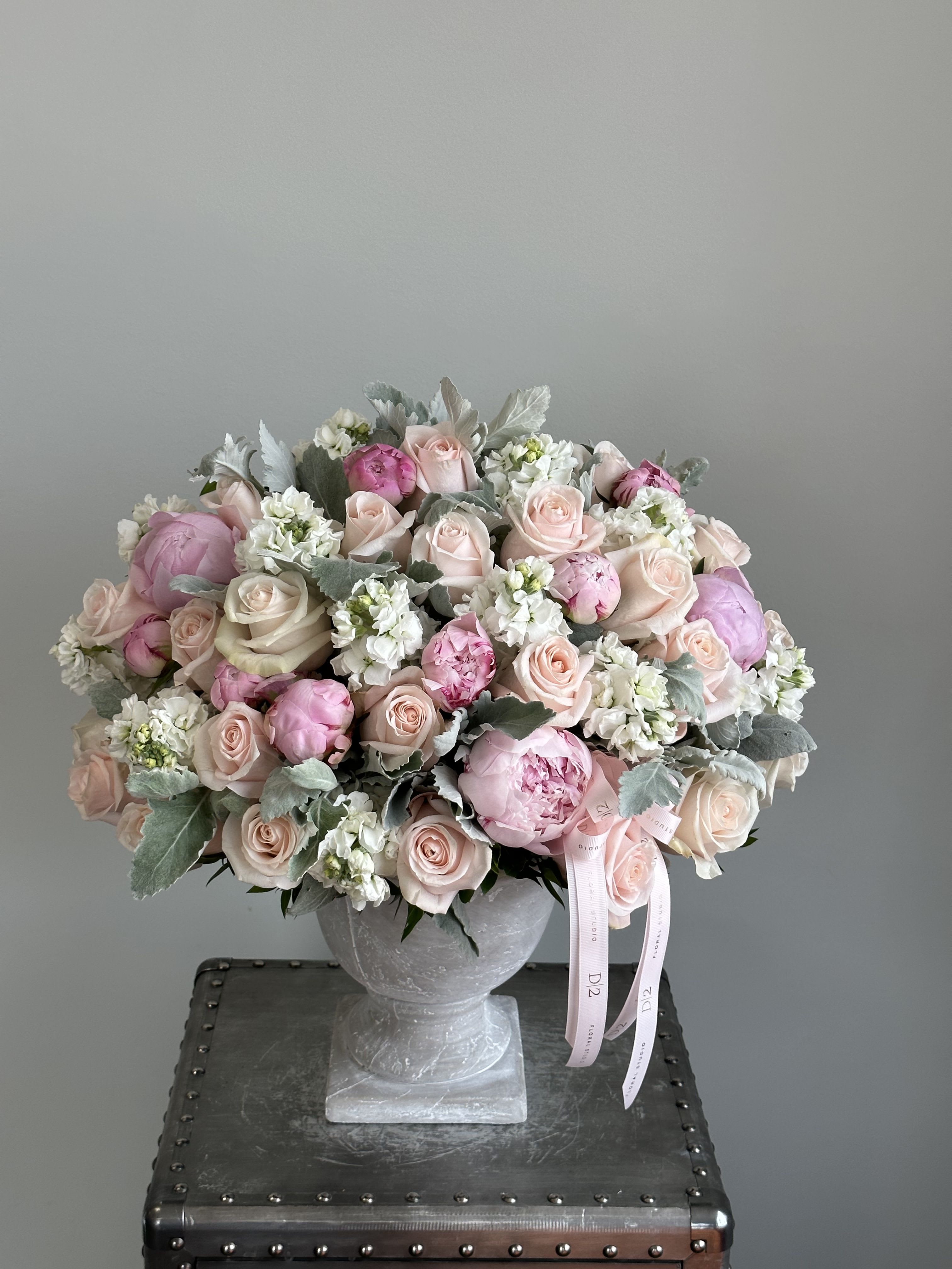 Pink and white rose bouquet in a gray pedestal vase