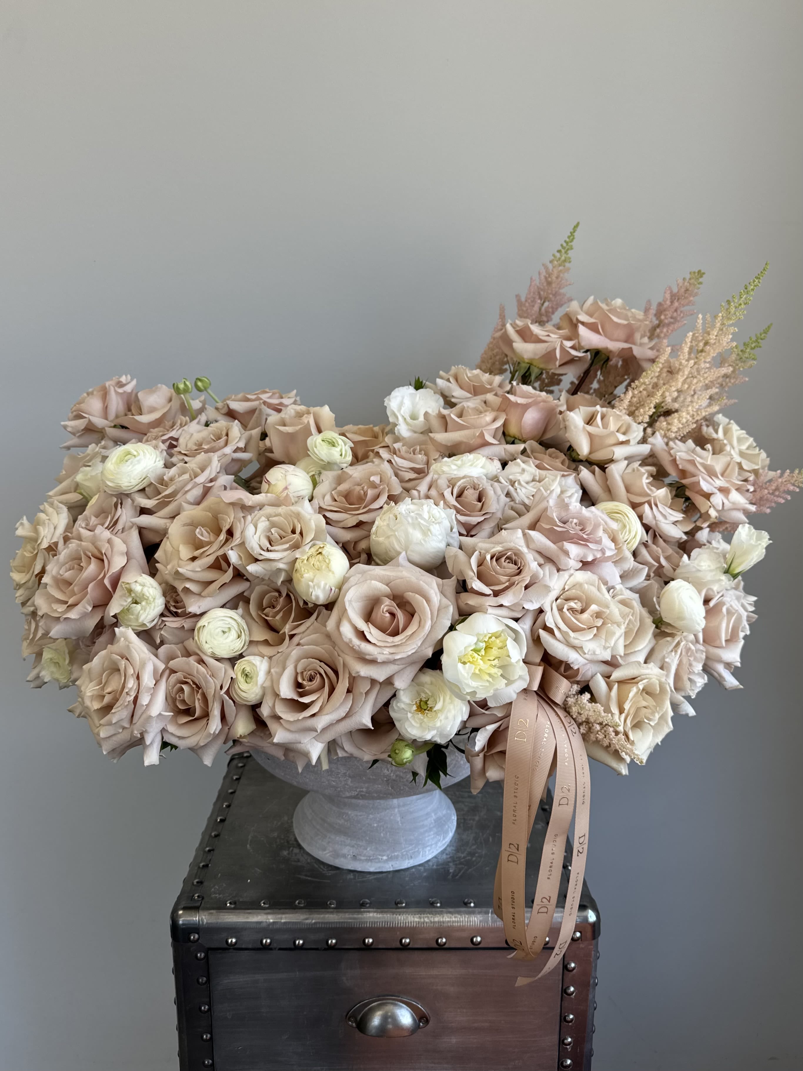 Blush rose arrangement in a gray pedestal vase with ribbon