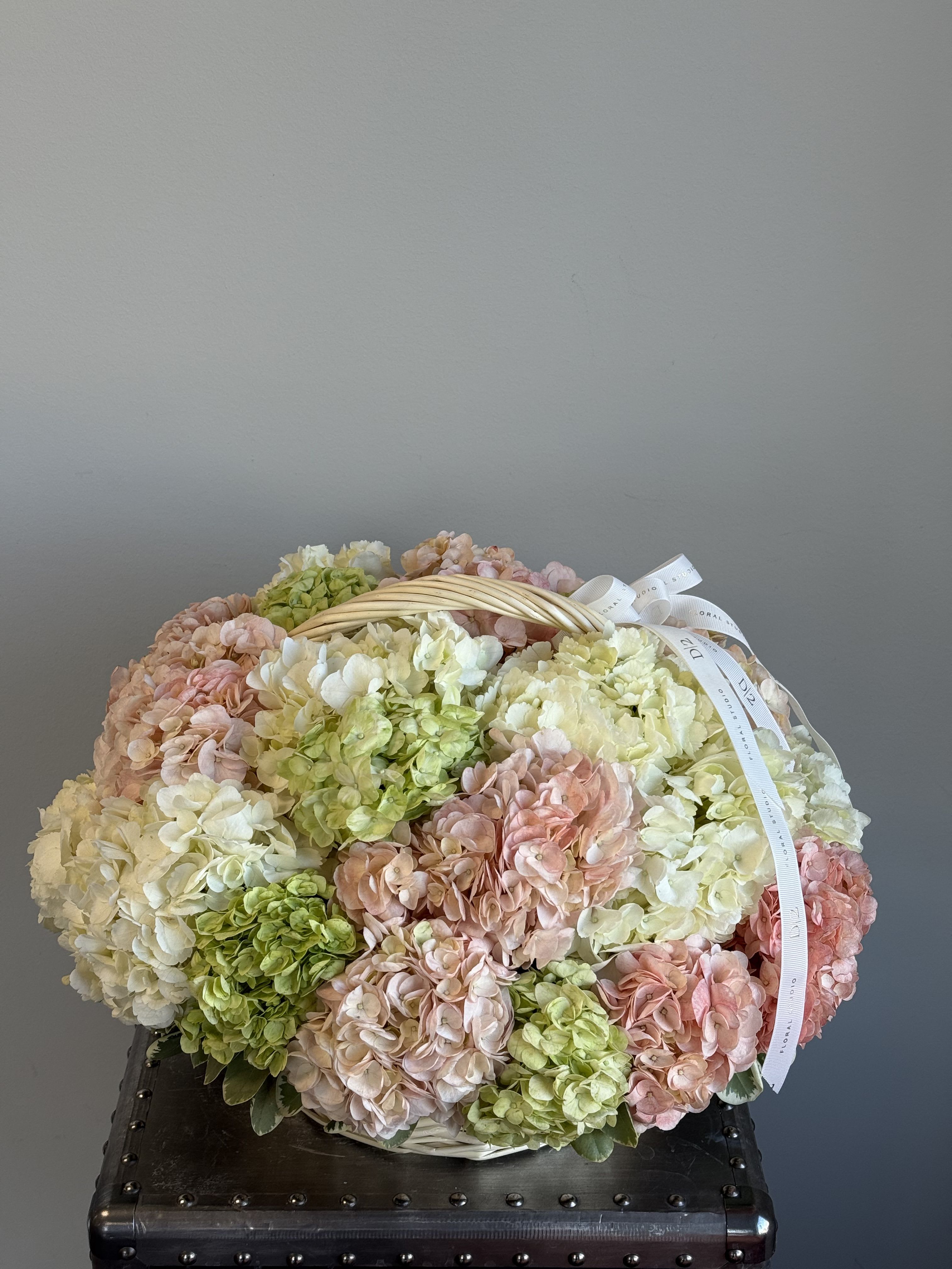 Basket of pastel hydrangeas with a ribbon handle