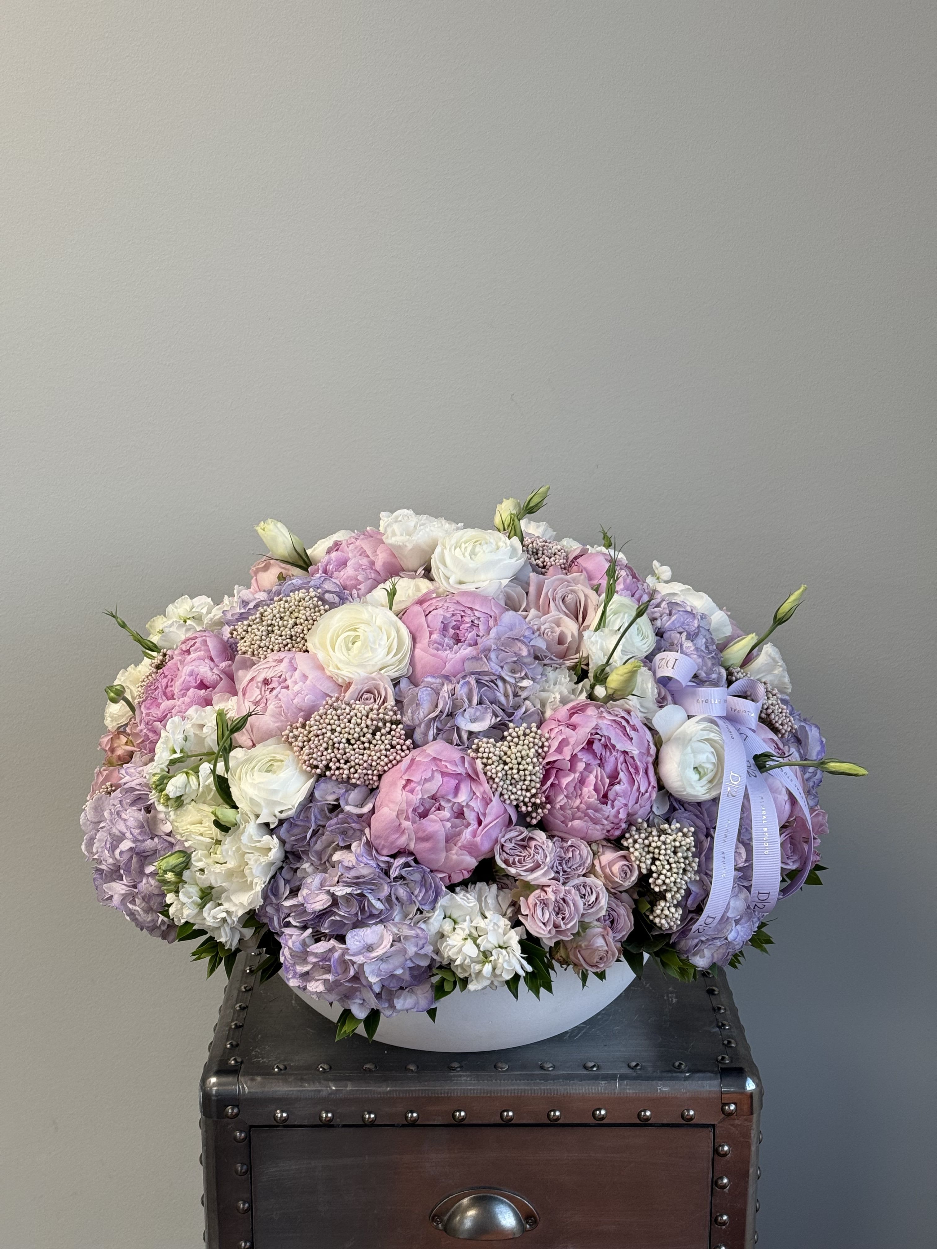 Large pastel bouquet of pink, lavender, and white flowers in a white bowl