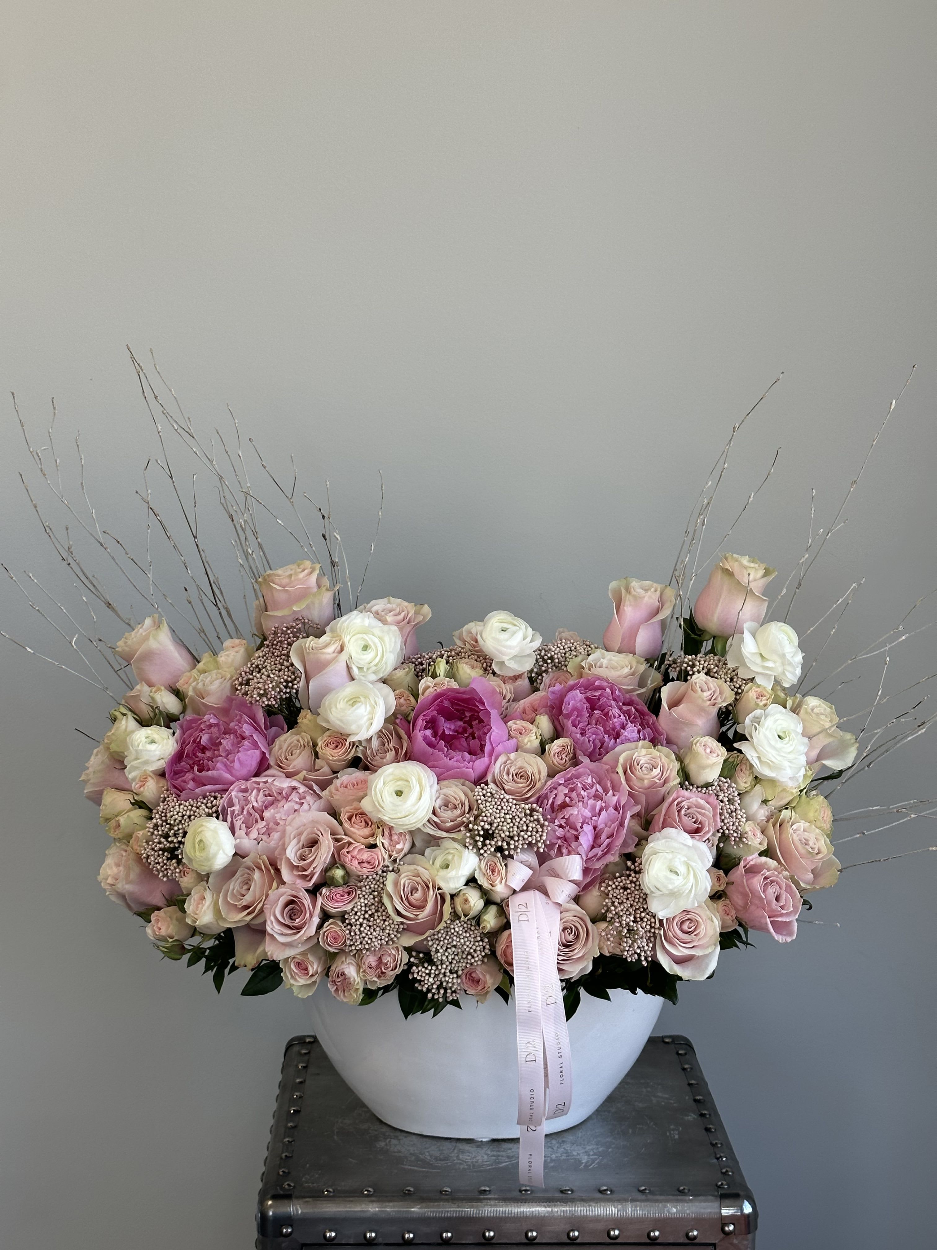 Large pink and white rose arrangement in a white bowl vase