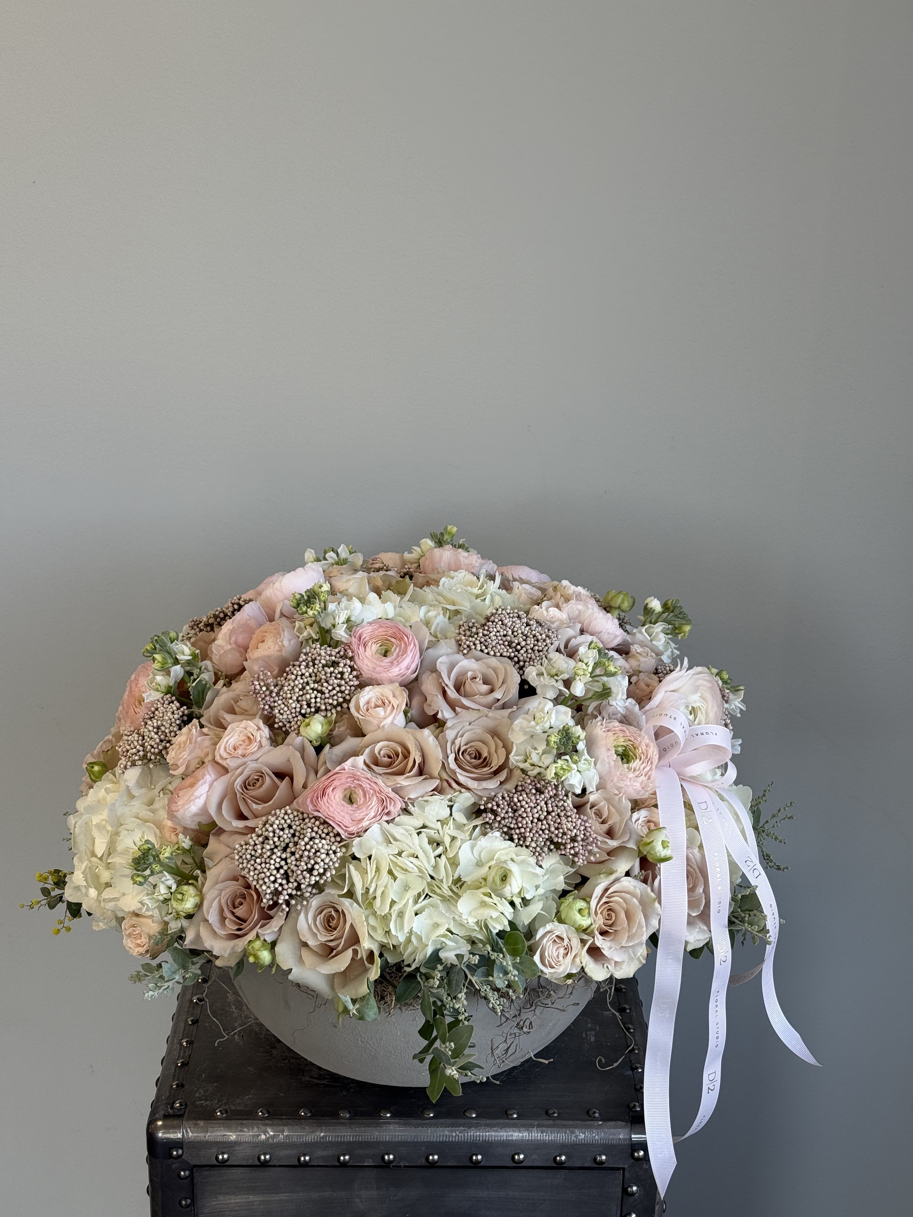Large pastel bouquet of roses, ranunculus, and hydrangeas with a ribbon