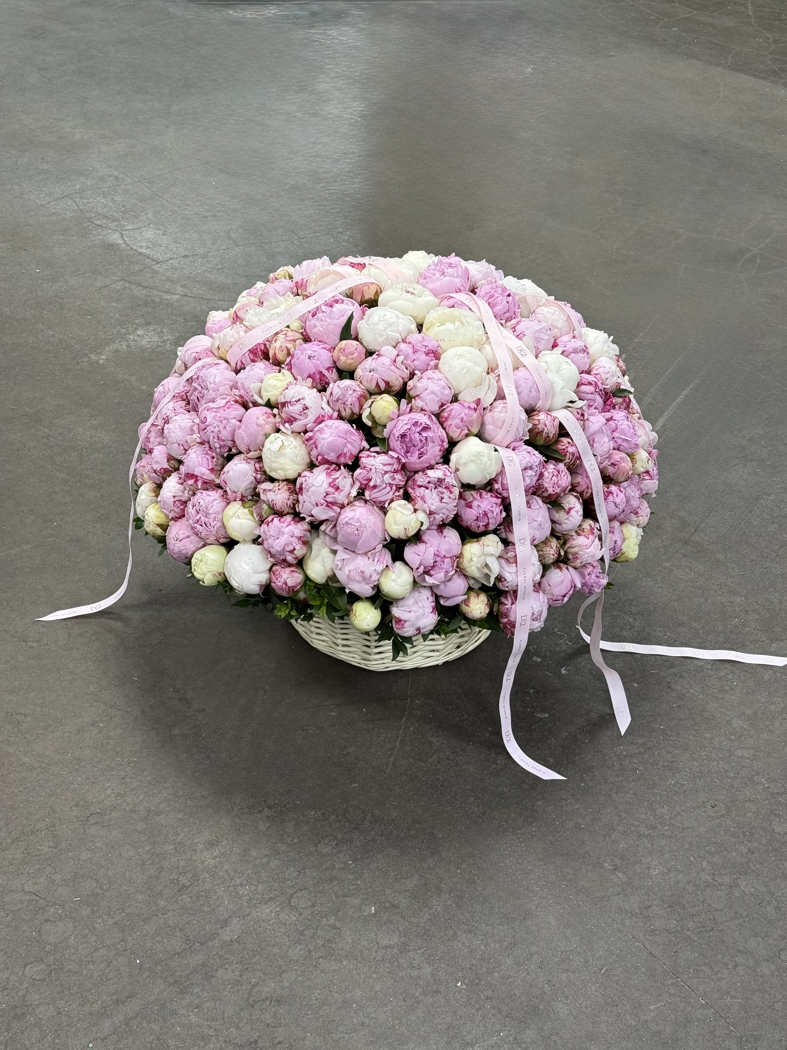 Large basket of pink and white peonies with ribbon streamers