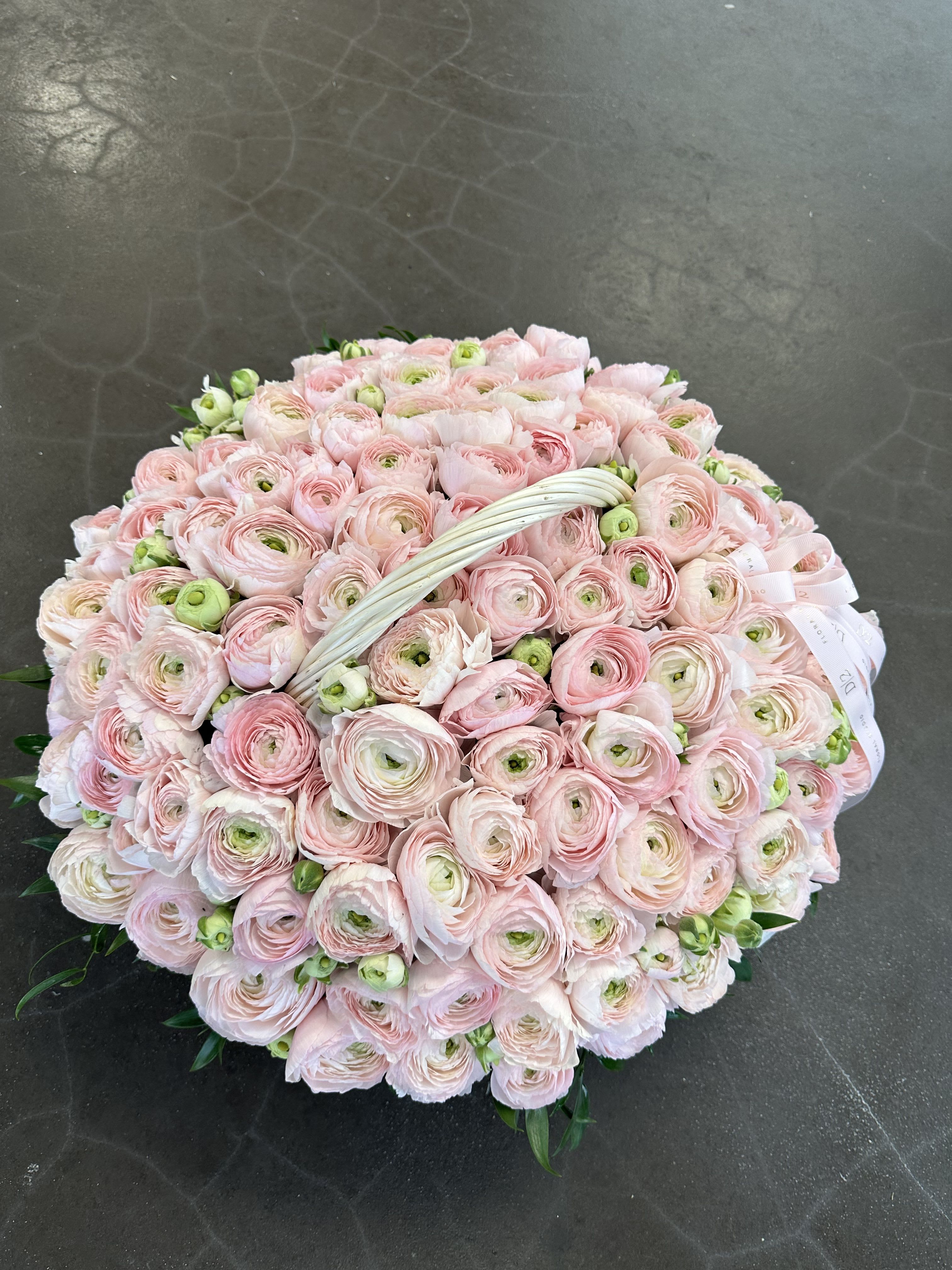 Large round bouquet of pale pink ranunculus with a white handle