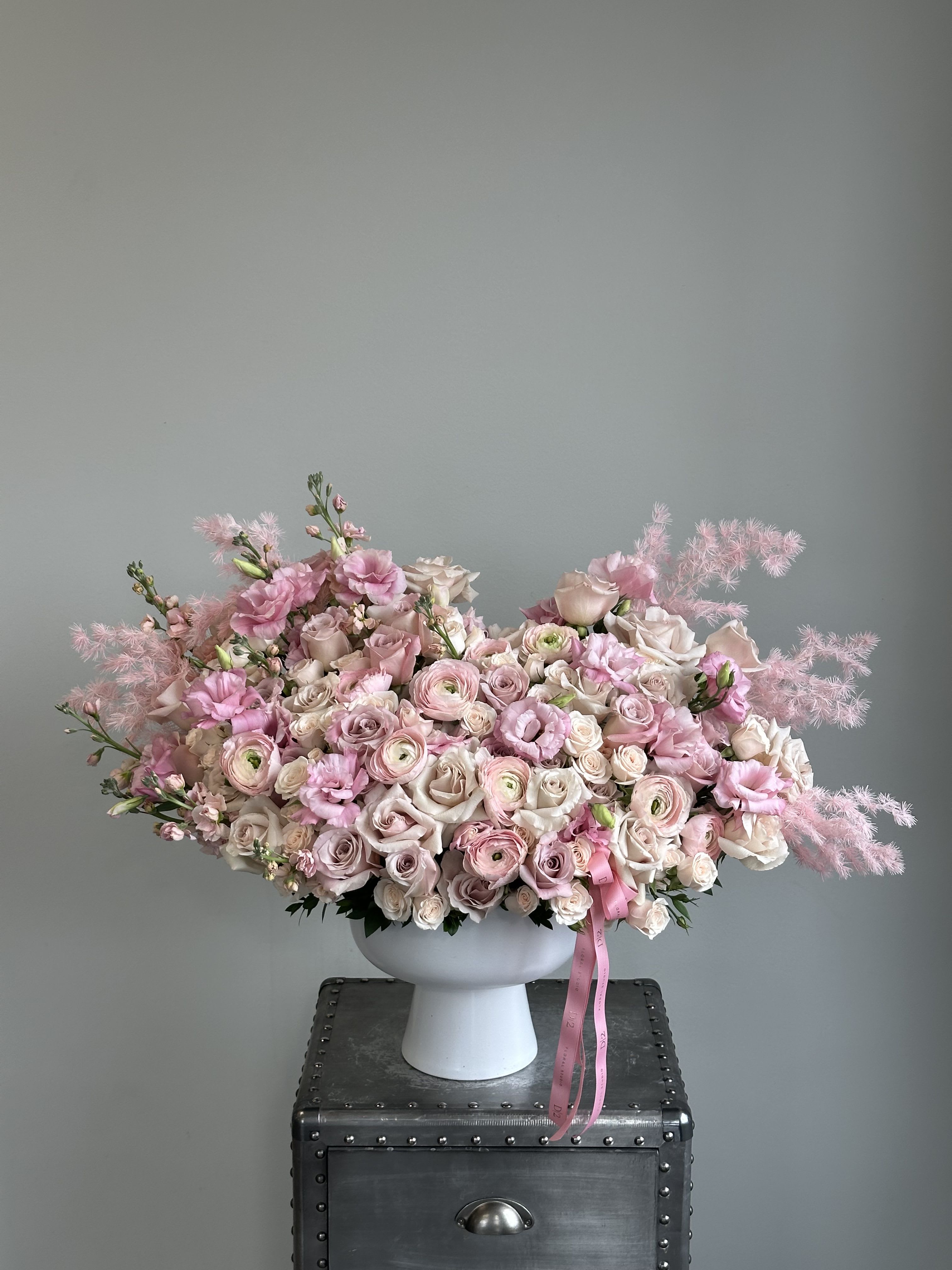 Large pink and white floral arrangement in a white pedestal vase