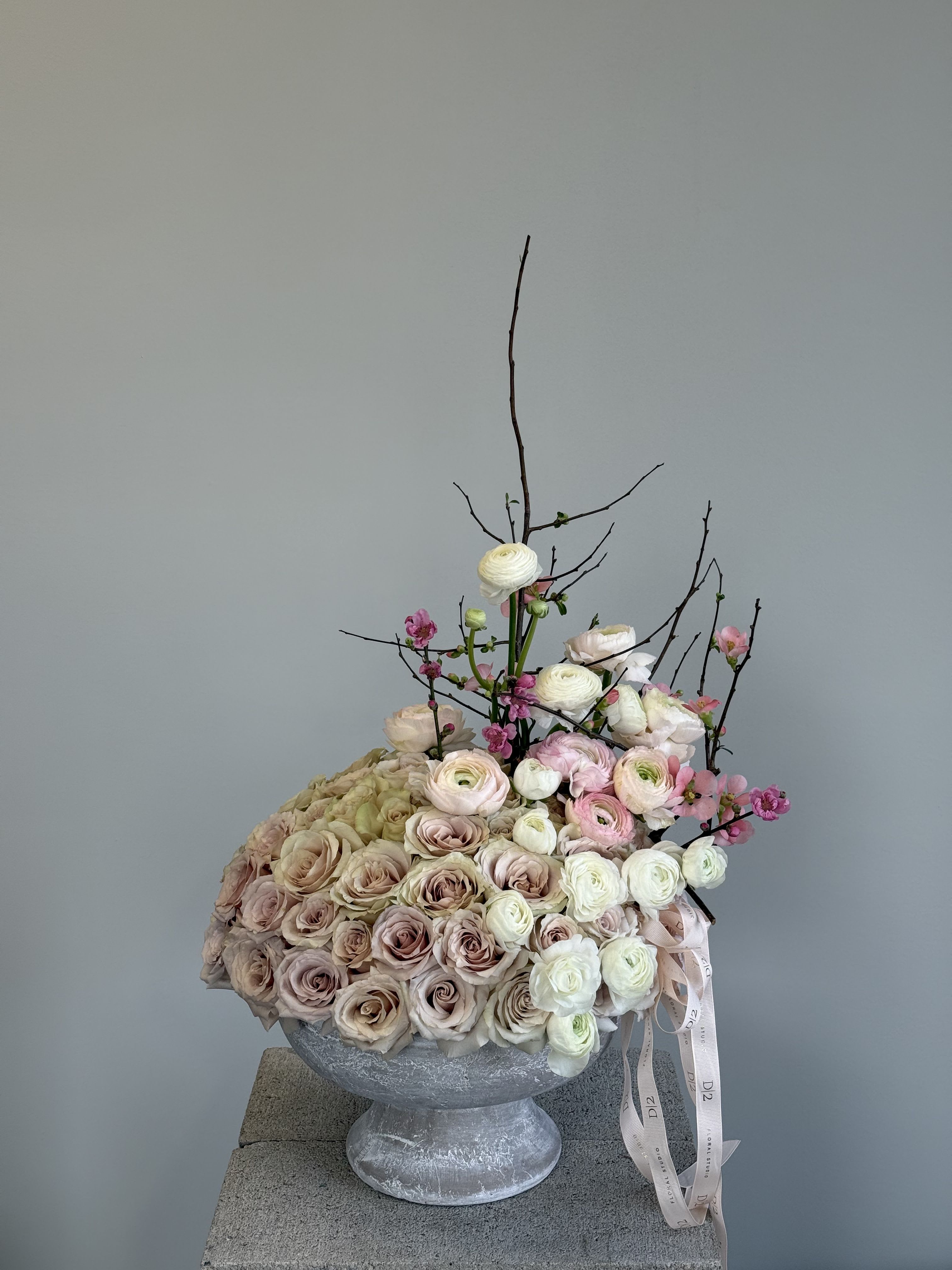 Large pastel rose arrangement in a gray pedestal vase