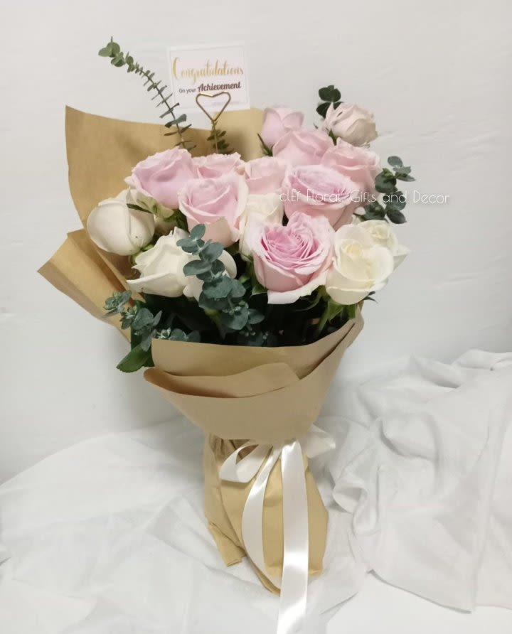 Pink and white rose bouquet wrapped in kraft paper with a ribbon