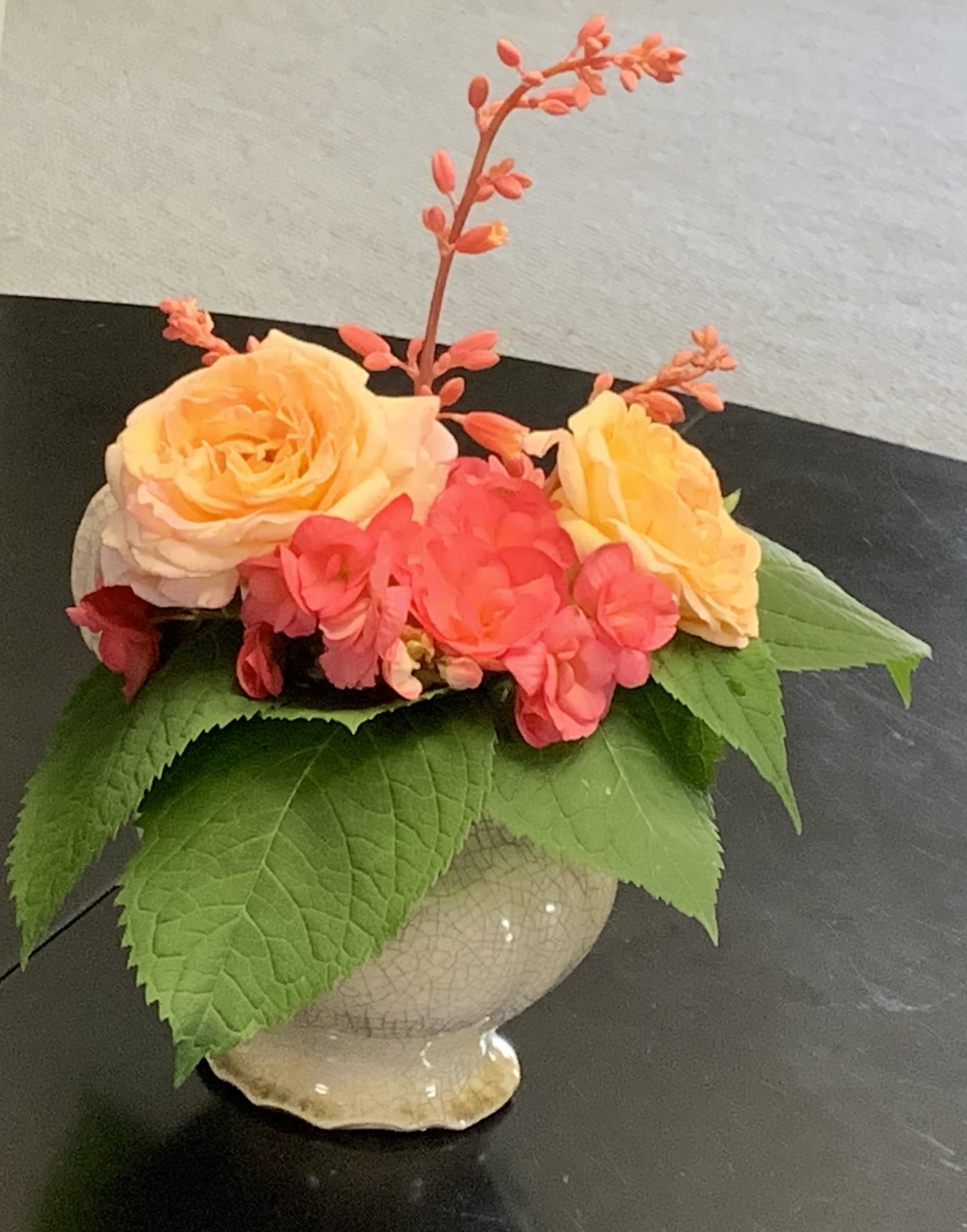 Small floral arrangement with peach and pink roses in a ceramic vase