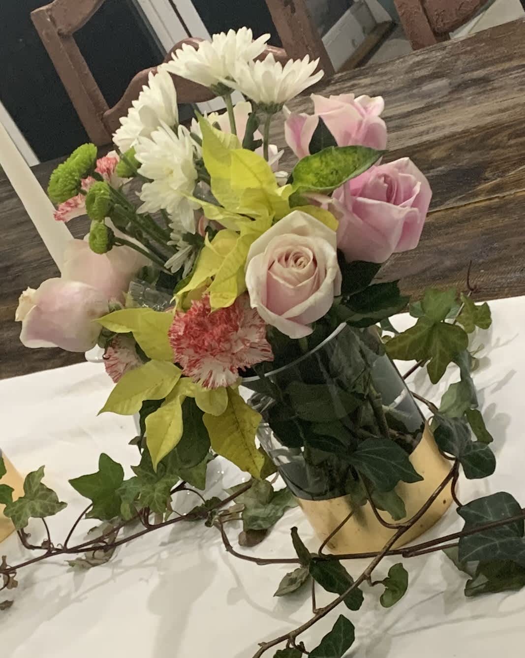 Pink roses and white daisies in a vase with ivy
