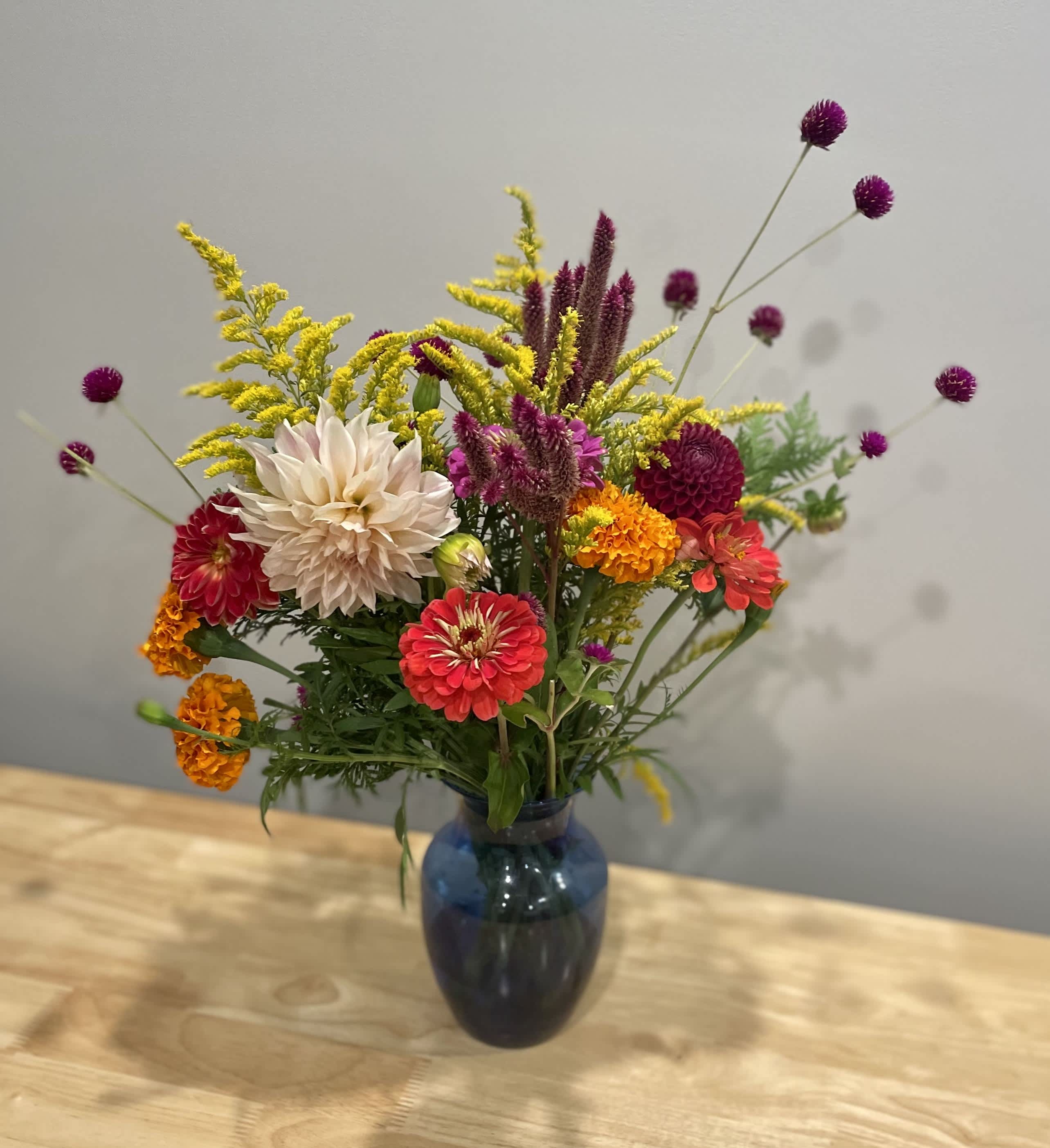Mixed bouquet of colorful flowers in a blue glass vase