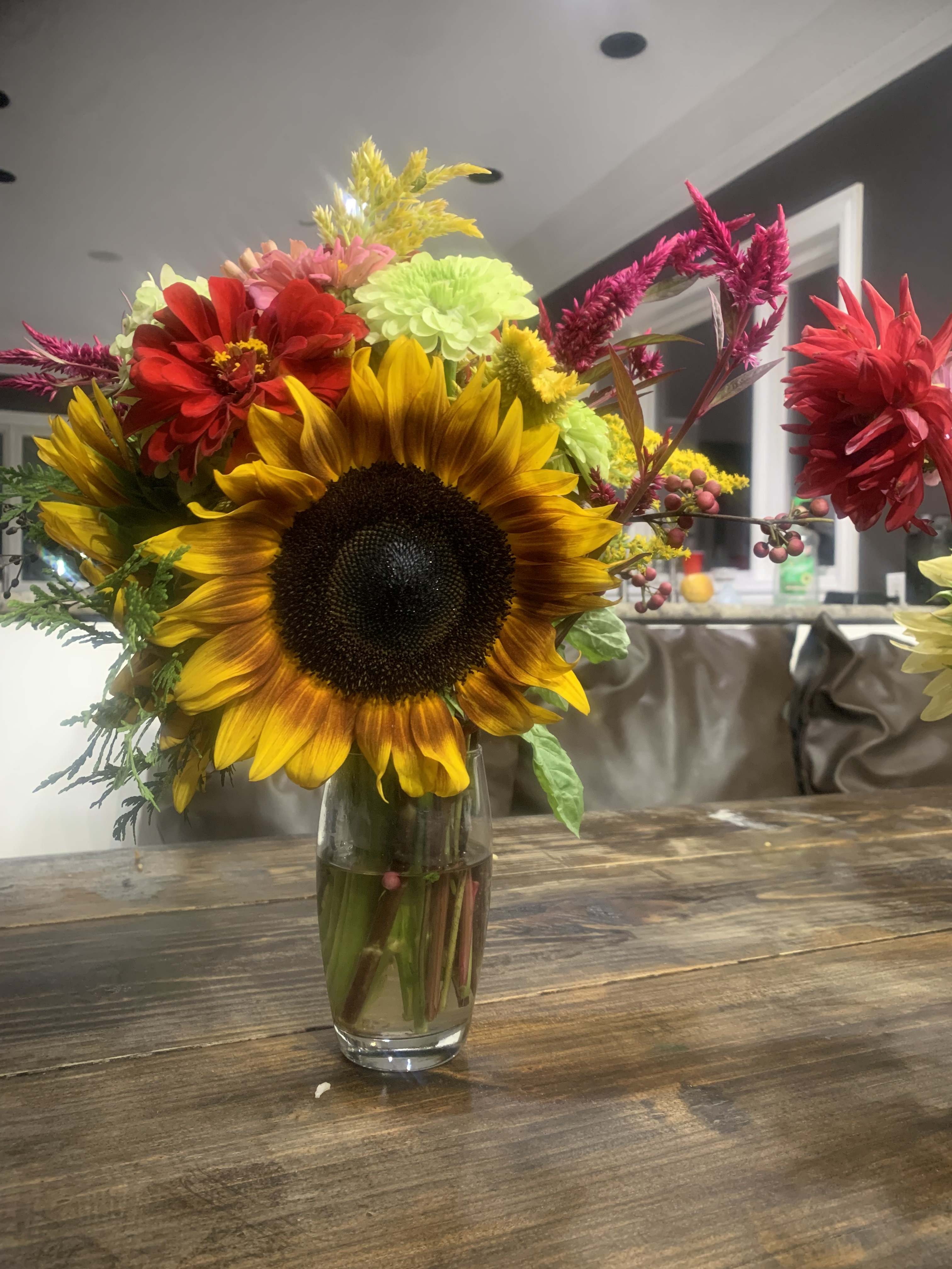Mixed bouquet with a large sunflower in a glass vase