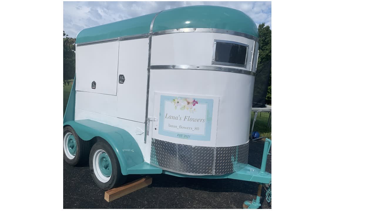 Teal and white flower trailer with a Lana's Flowers sign