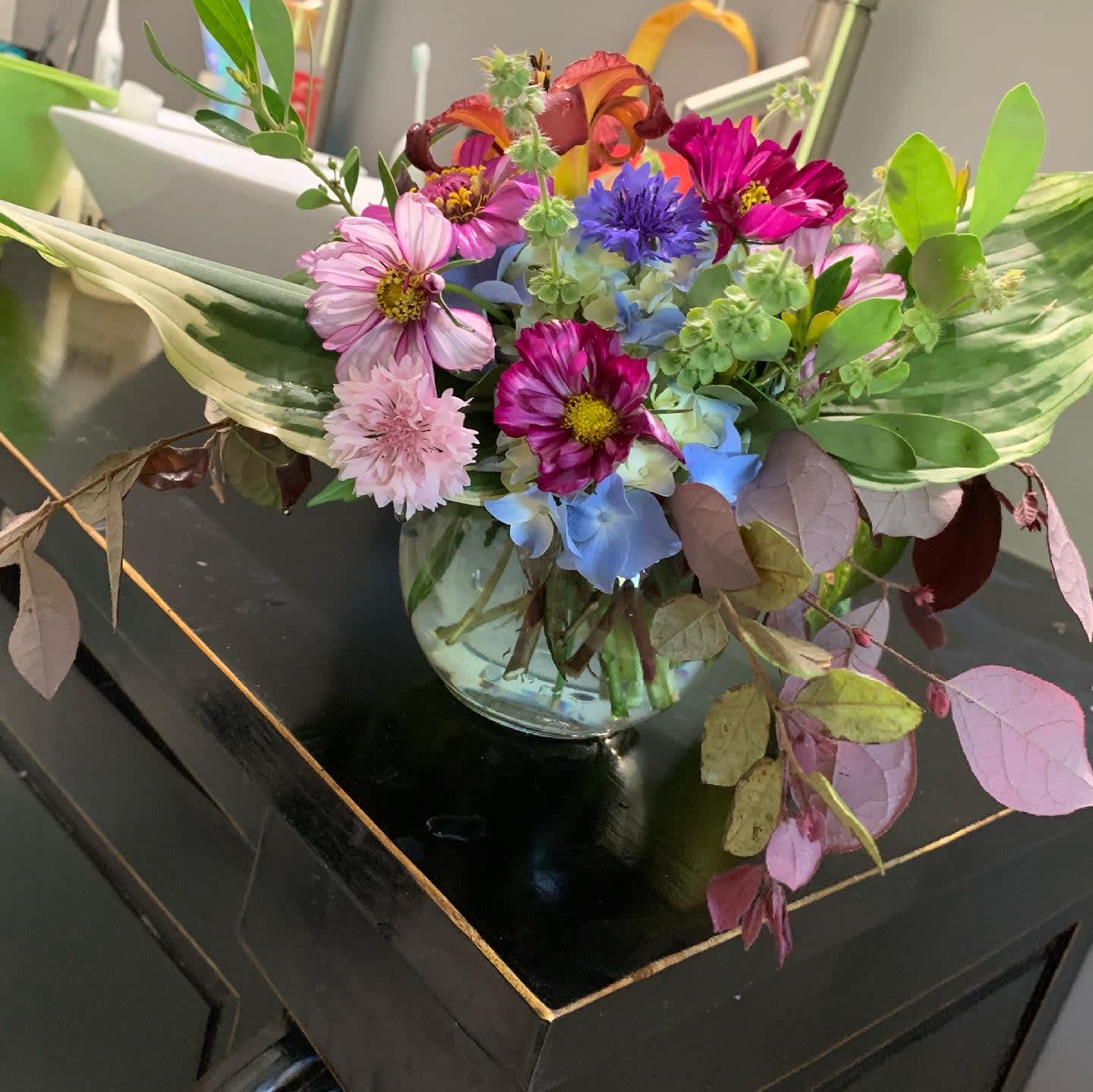 Mixed bouquet of pink, blue, and purple flowers in a glass vase