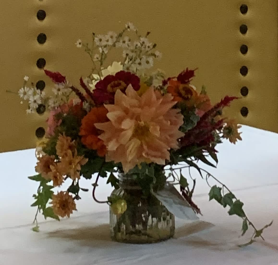 Mixed floral arrangement in a glass vase with peach, red, and orange blooms