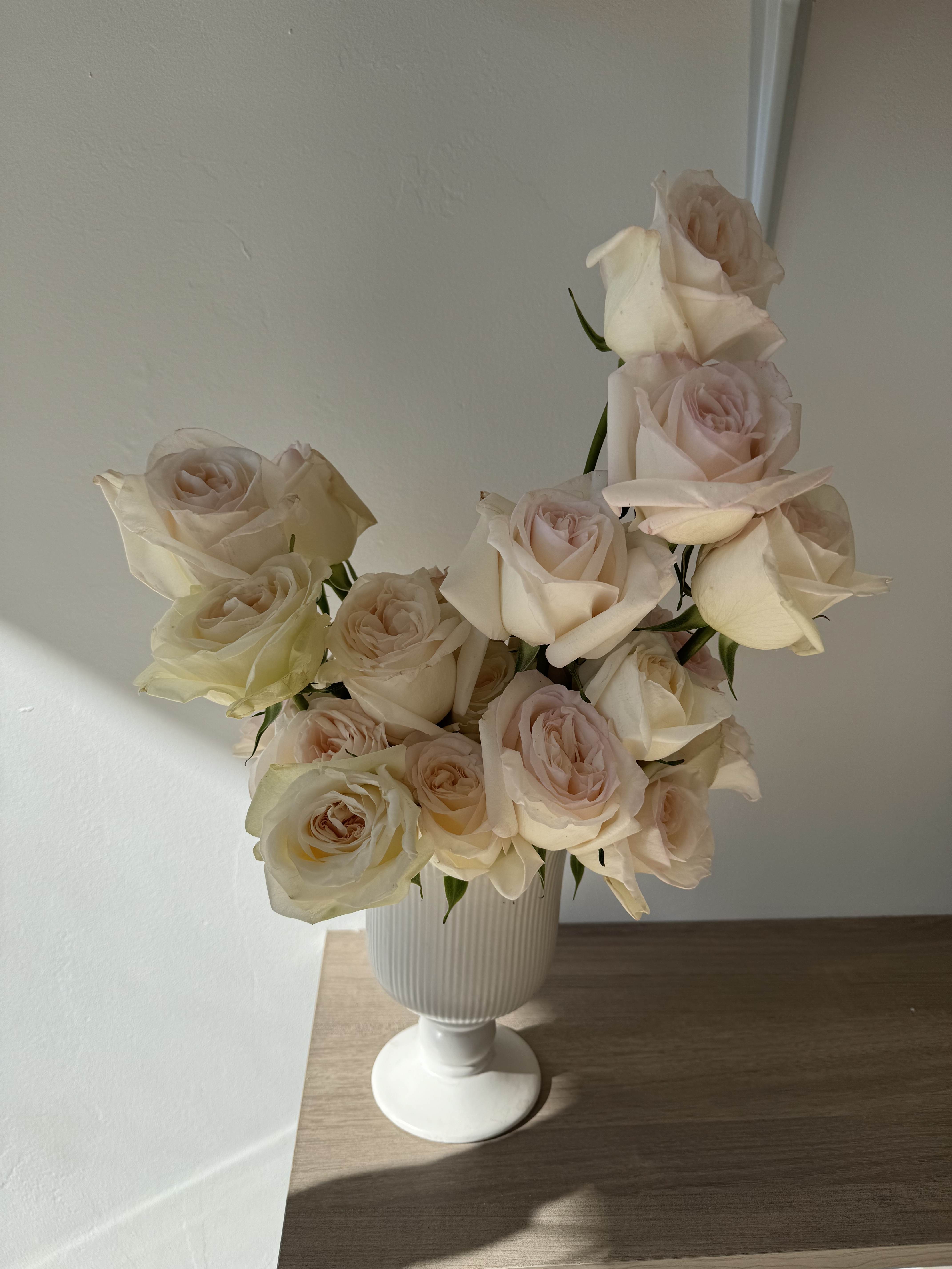 Cream roses arranged in a white pedestal vase